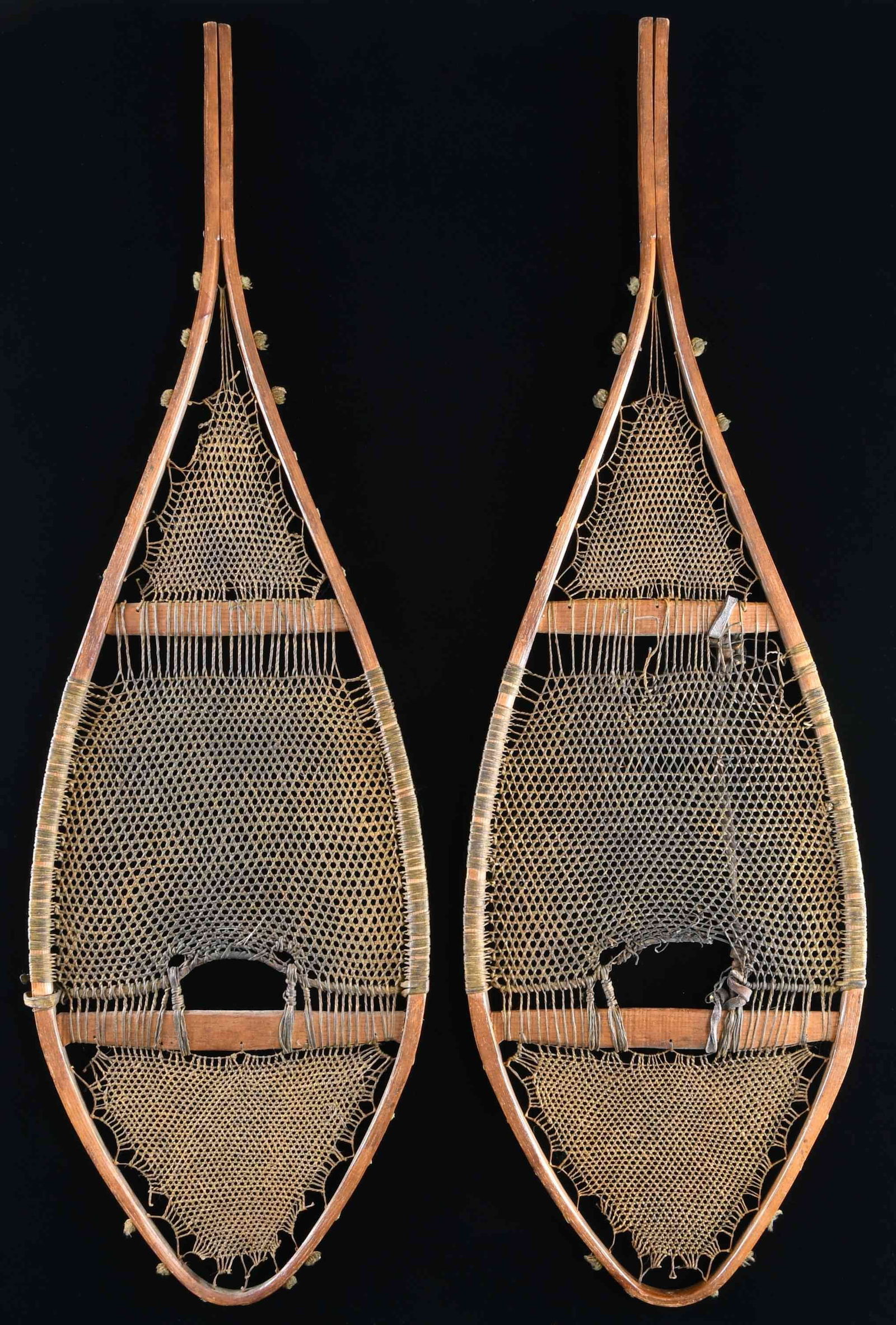 NATIVE AMERICAN SNOWSHOES.: This pair of Native American snowshoes likely originated with the Ojibwe tribe of the Quebec and Great Lakes area. The shoes measure approx. 44" long x 14" wide. They have finely and intricately woven