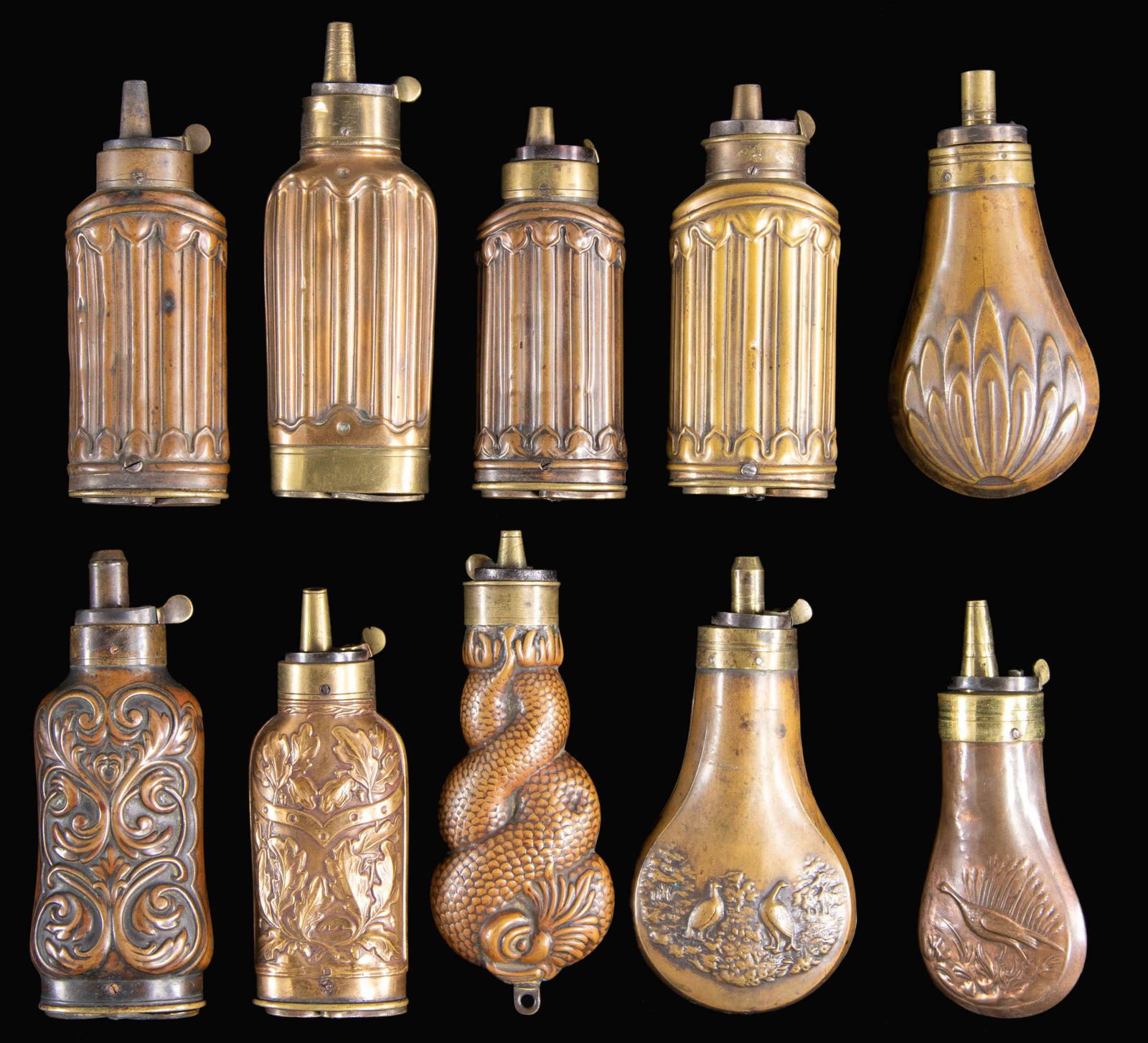 TEN DECORATED PISTOL POWDER FLASKS.: Ranging from 4" to 5", six have cap & ball compartments in bases, one scarce twisted dolphin design. CONDITION: good to very good overall. PROVENANCE: The Esteemed Norm Greenberg Collection. (02-24848