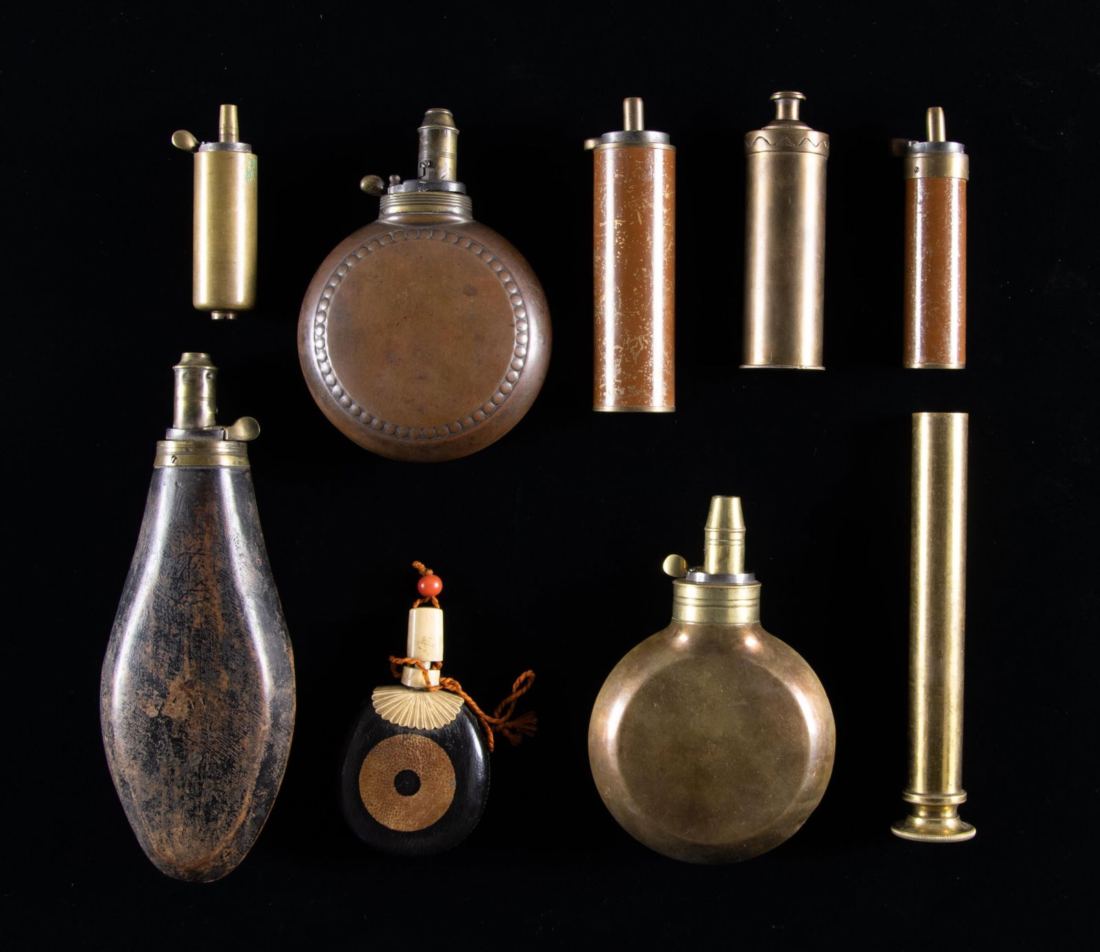 GROUP OF 9 UNUSUAL POWDER FLASKS.: Group includes two 4" round flasks, 8" carved wood, small Japanese leather covered gold paint & bone, two 1" cylindrical flasks measuring 3" & 4"; two 1.25" diameter 4" & 5"; 6.5" brass telescoping po