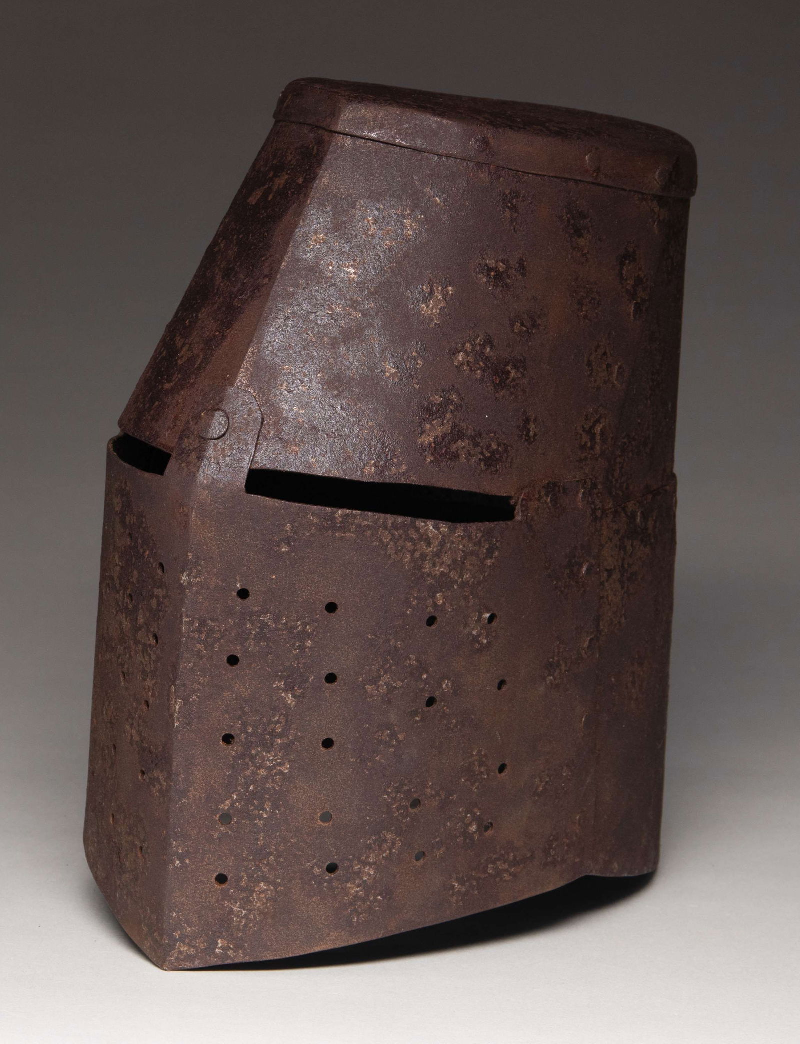 VICTORIAN COPY OF AN ENGLISH MEDIEVAL: HELMET. This imposing medieval iron helmet is a Victorian copy of a popular style known as a great helm. The helmet is just shy of 12" tall and also nearly 12" from front to back. It shows riveted con