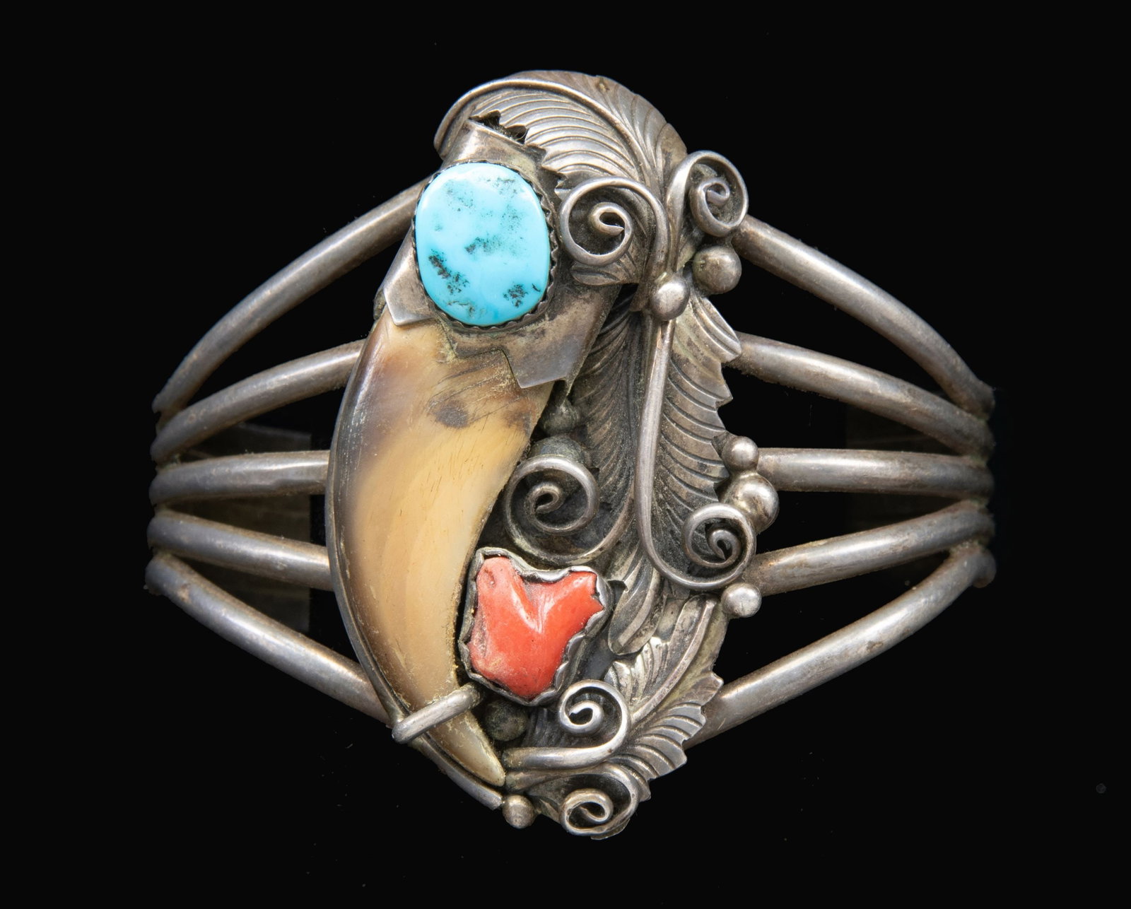 "M. TSOSIE" SIGNED STERLING NAVAJO TURQUOISE, RED: CORAL & BEAR CLAW BRACELET. 2.25" x 1.25" medallion decorated with a bear claw, red coral & turquoise, signed "M. TSOSIE", 55 grams. CONDITION: good. (02-25619-5/JS). NON-GUN. $200-400.