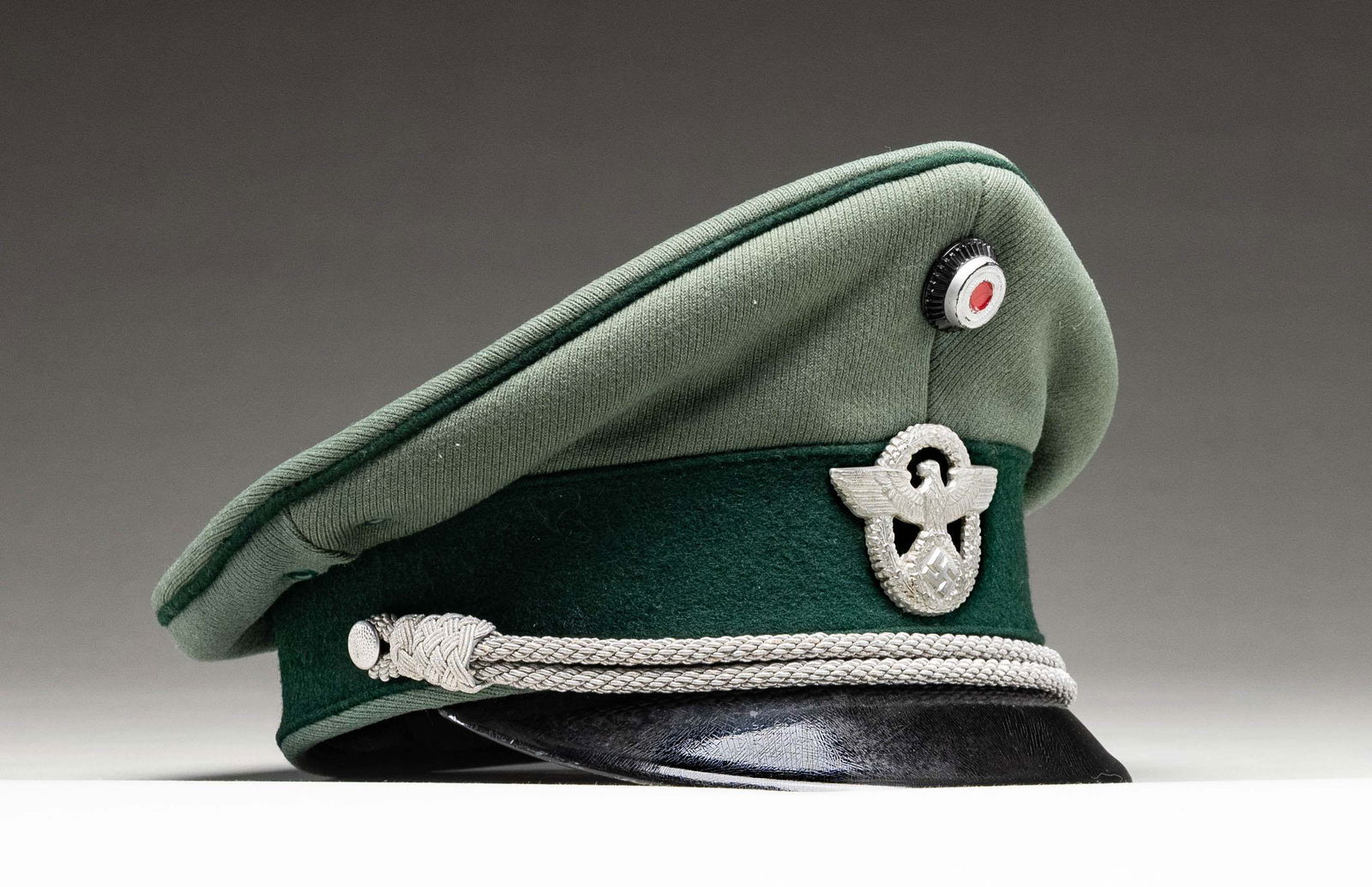 WWII GERMAN POLICE VISOR CAP.: A fine example of a WWII German Police official's' visor cap with a sage green crown and a dark green band. The cap is piped in green With a National Cockade on the top and an aluminum police eagle an