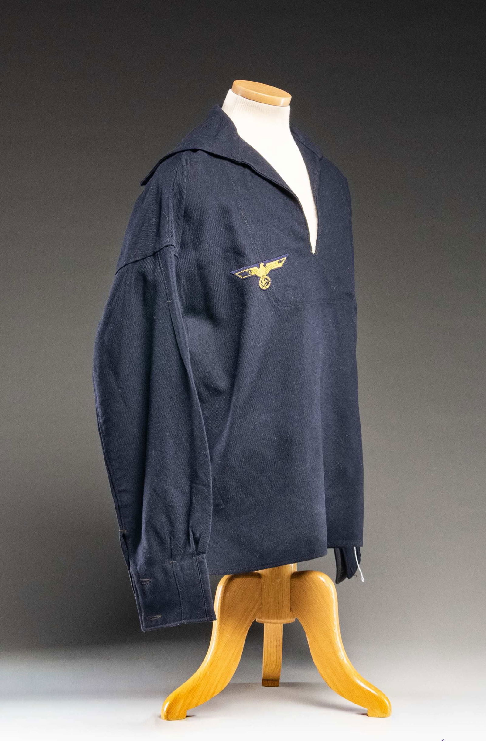 WWII GERMAN KREIGSMARINE JUMPER.: A good WWII German Kriegsmarine enlisted jumper in dark navy blue wool. There is a yellow on blue eagle at the right breast. Each sleeve has 2 buttons at the cuff. There is a small white cotton tag in