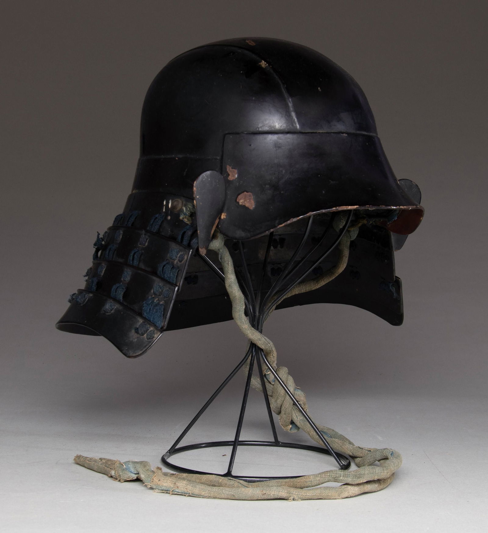 JAPANESE HINENO ZUNARI KABUTO WITH FOUR SHIKORO.: This black enameled Hineno Zunari Kabuto was made of three to four iron plates in a simple design to facilitate mass production. It has an integral mabishashi and 4 shikoro with smaller fukigaeshi.