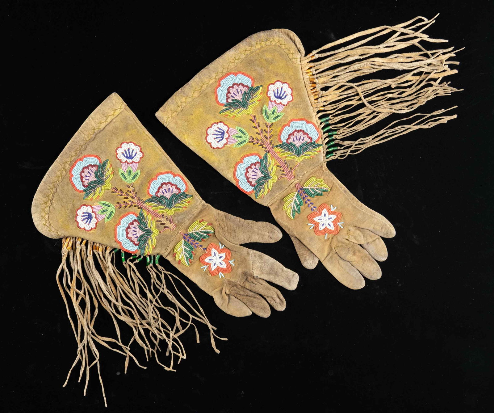 STRIKING PAIR OF NATIVE AMERICAN BEADED & FRINGED: GAUNTLETS.These exceptional gauntlets likely date from the later 1800s and measure about 16" in length by about 9 1/2" at the cuffs. The fringe extends 9" from the body of the gauntlet. Both