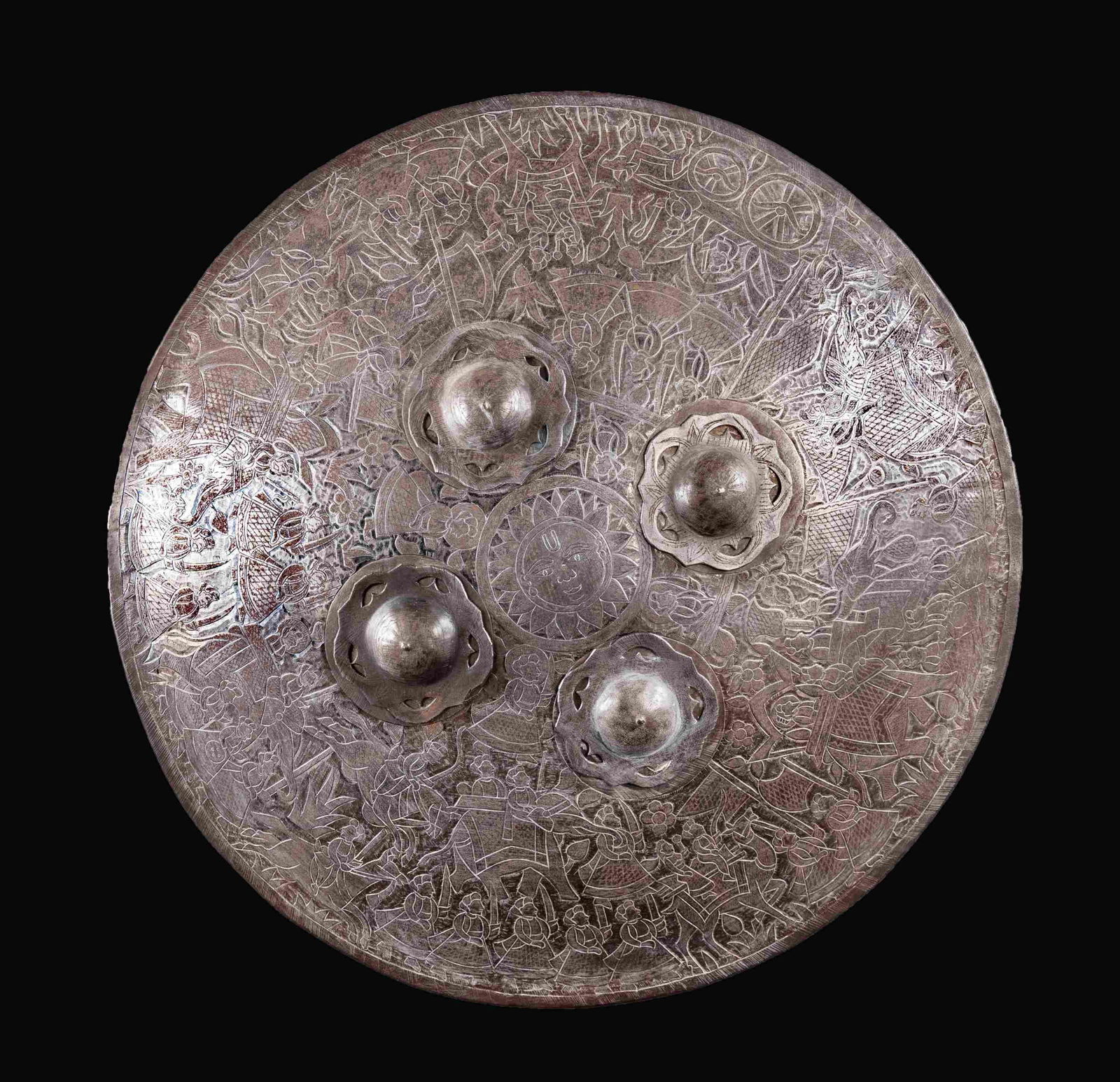 INDO-PERSIAN SHIELD OF THE 18th OR 19th CENTURY.: This shield has a diameter of 24 3/4" and is profusely decorated with Indo-Persian scenes including elephants, soldiers, and flowers including a central multi-rayed sun. There are four raised 4 1/4"