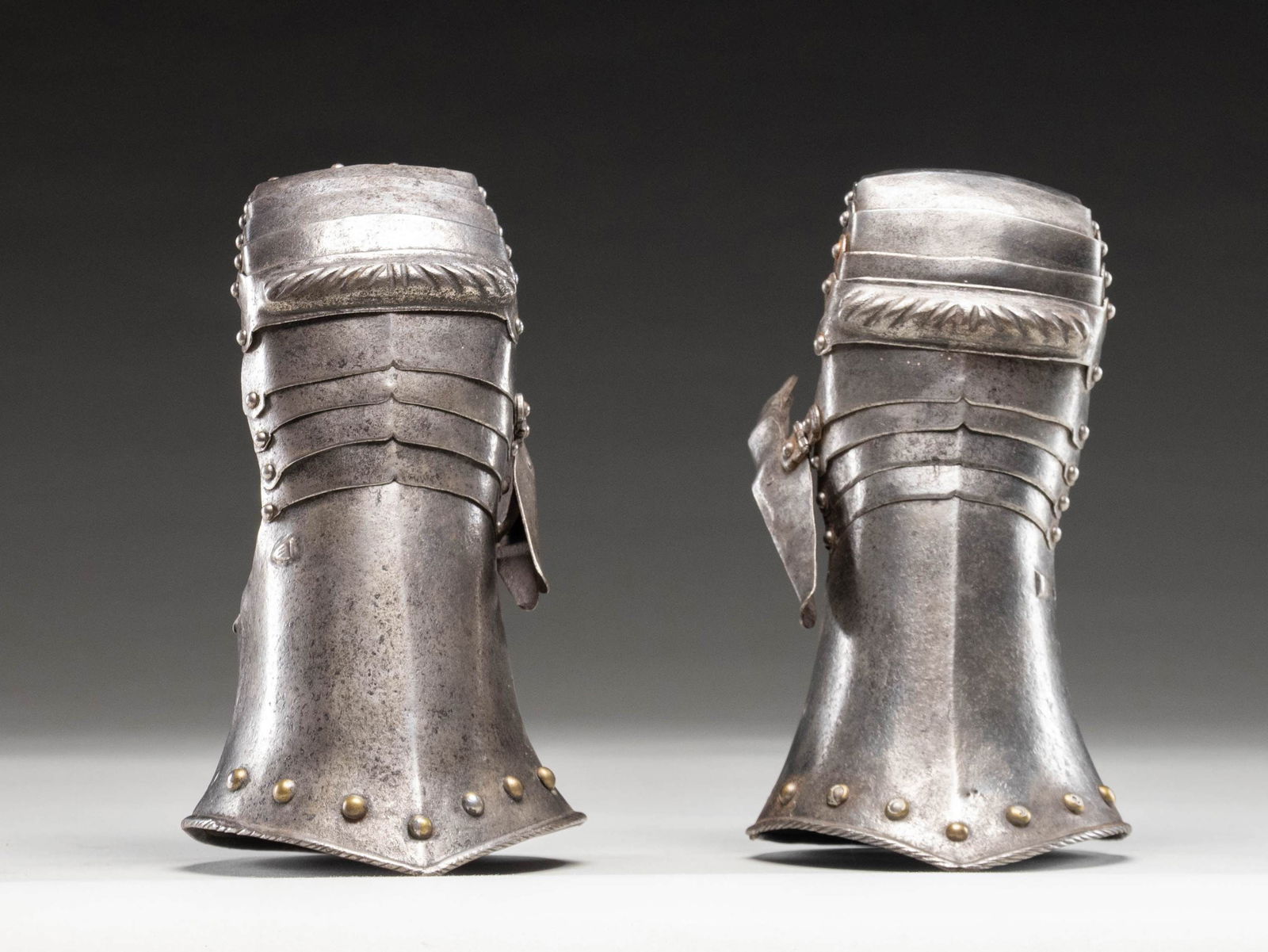 MID 16th CENTURY GERMAN MITTEN GAUNTLETS.: A fine matched pair of iron mitten gauntlets of German origin, possibly from Nuremberg. Each gauntlet is approx 10 1/2" in length and 5 1/4" at the peaked cuff. There are numerous brass rivets at the