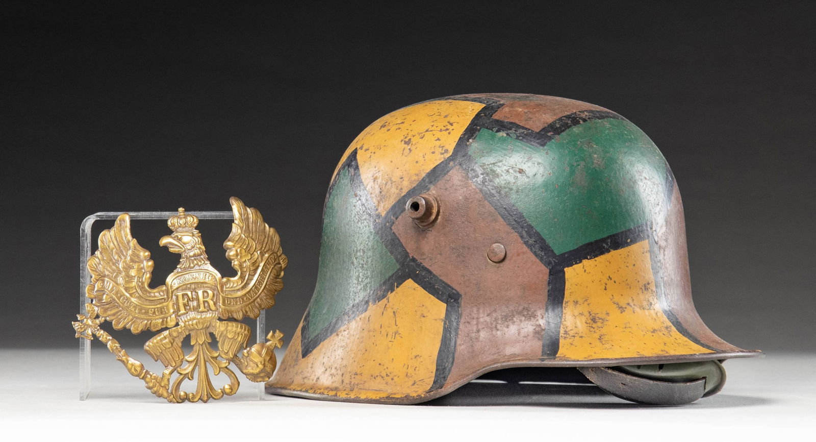 WWI GERMAN CAMOUFLAGE HELMET & PRUSSIAN FRONTPLATE: 1) A model 1918 German steel helmet with a fine camouflage painted motif. Colors include green, brown, and mustard with black borders. Interestingly, this example has a neatly painted black and white