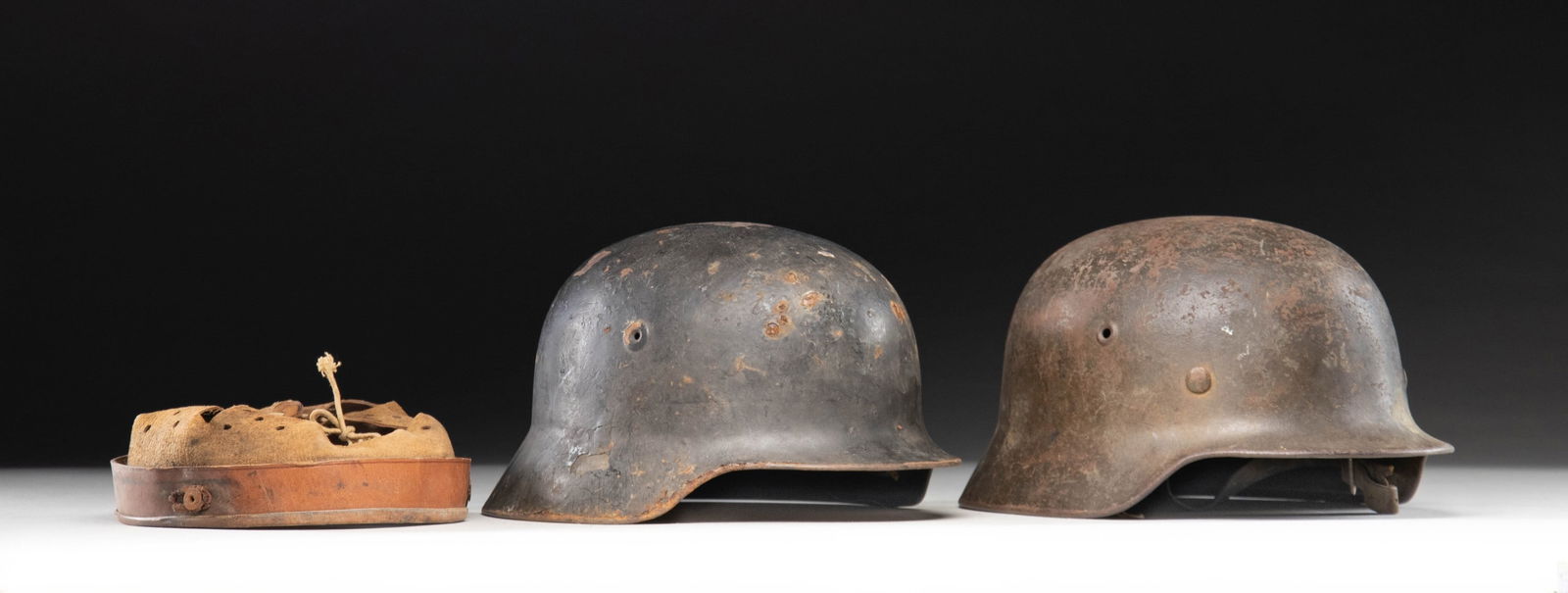 2 WWII GERMAN HELMETS AND AN EXTRA LINER.: 1) WWII German M1940 single decal Wehrmacht helmet with a dark green painted finish and a Wehrmacht eagle decal on the left side. The helmet is stamped on the inside rear "222_" and on the inside