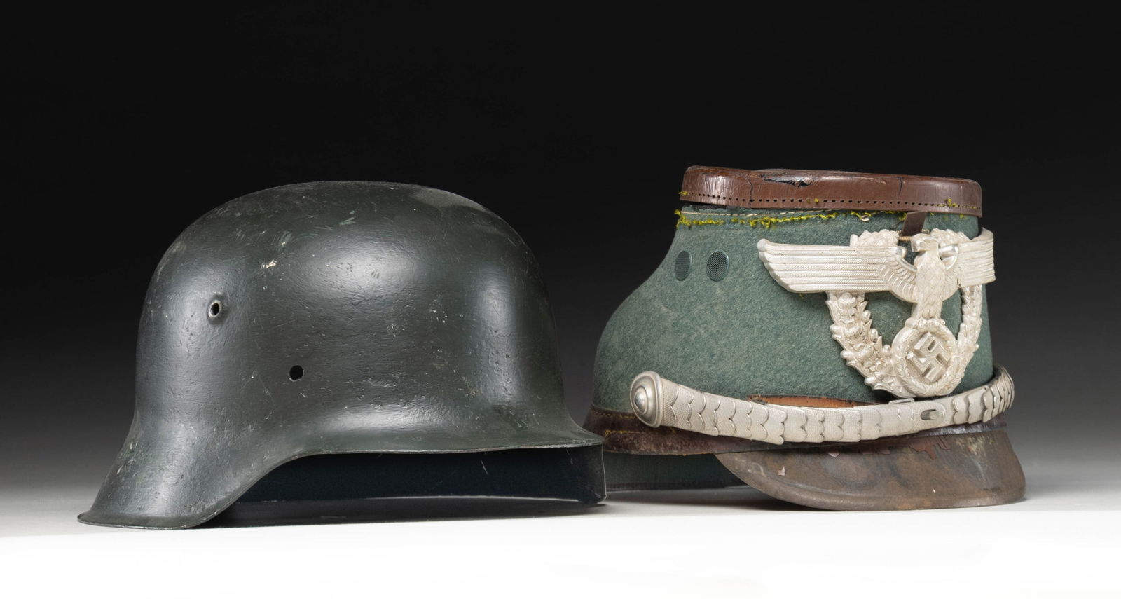 1 WWII GERMAN HELMET SHELL AND 1 POLICE SHAKO.: 1) WWII German M1942 helmet. This is the shell only that has been cleaned and repainted recently. No marks are visible. CONDITION: light wear as restored. 2) WWII German Police shako with a green