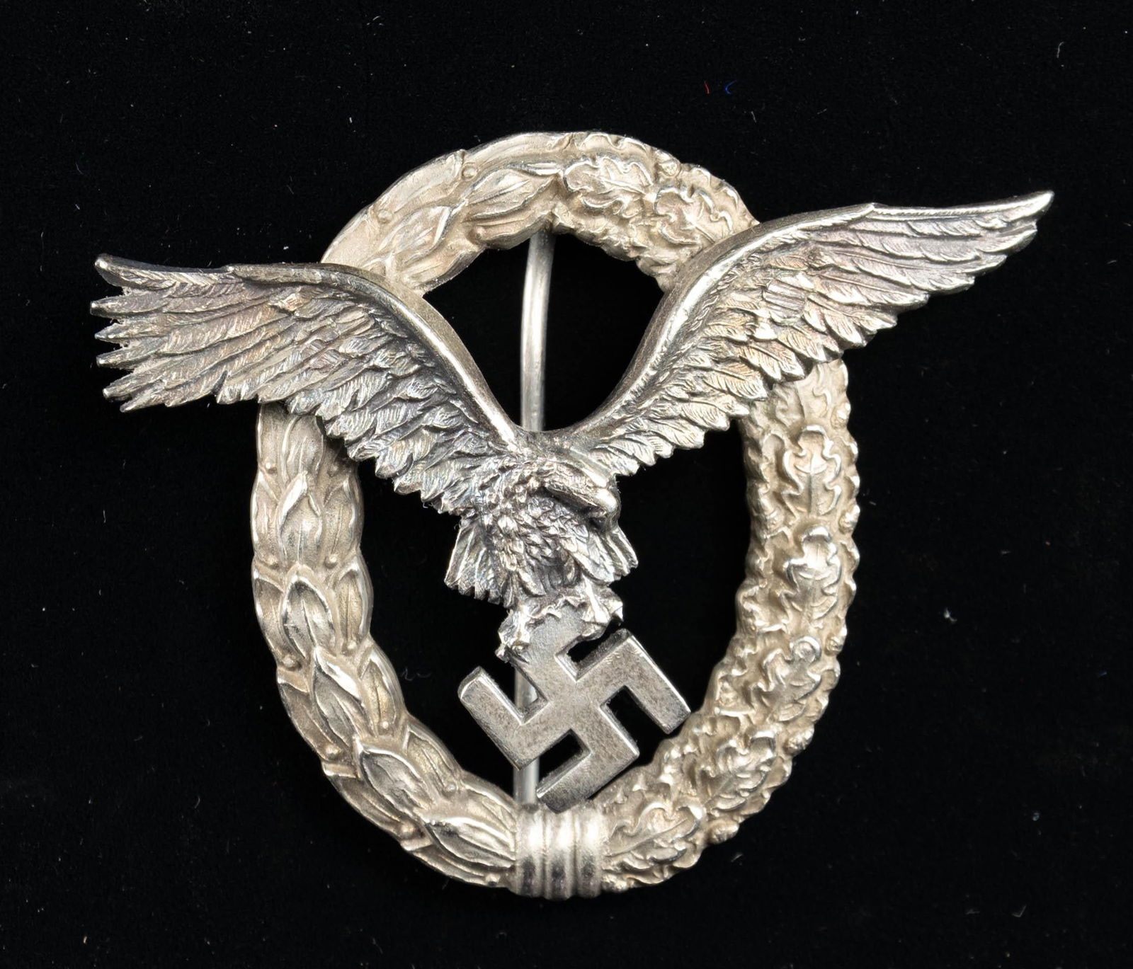 WWII GERMAN LUFTWAFFE PILOT OBSERVERS BADGE.: A fine example of a WWII German Combined Pilots and Observers Badge showing a spread wing eagle grasping a Party symbol surmounting a laurel and oak leaf wreath. The reverse has a narrow pin with 2 ri