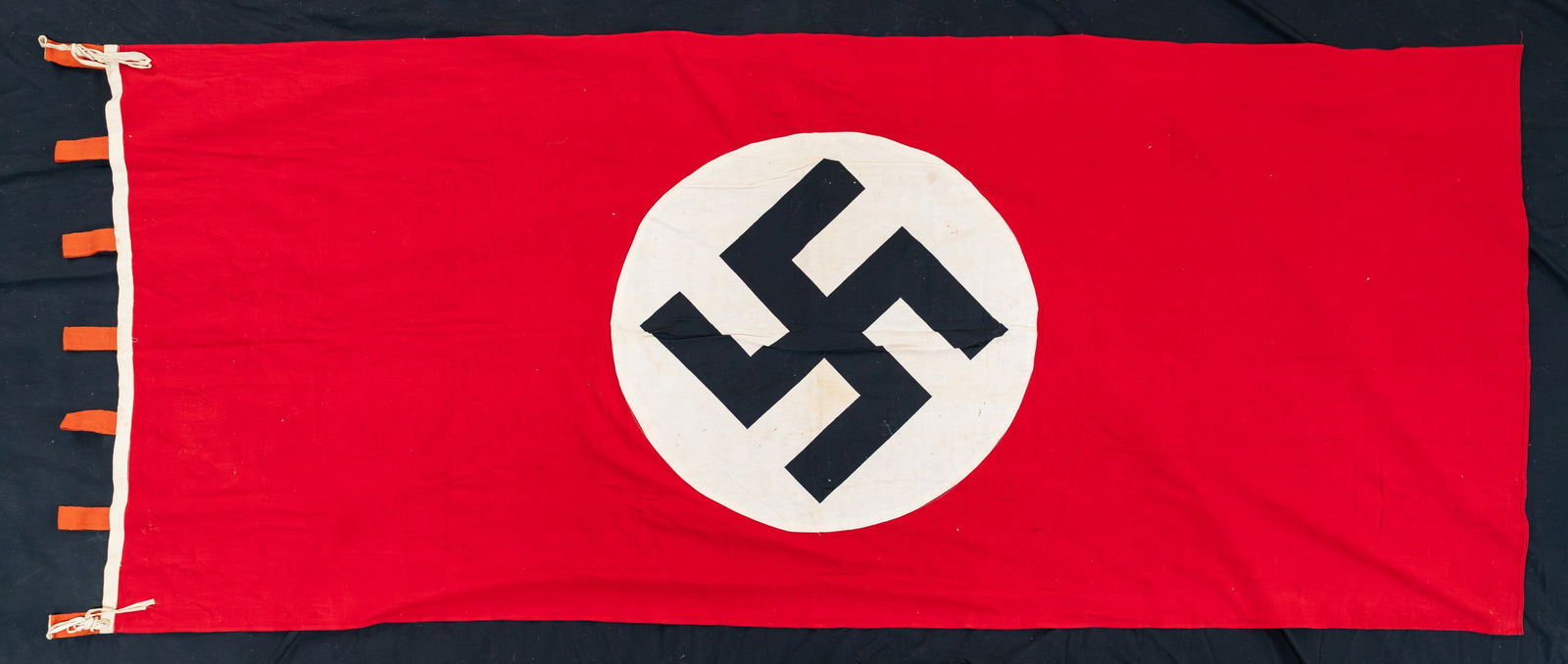 WWII GERMAN PARTY FLAG.: A good size WWII German Party flag or banner measuring about 92 1/2" x 40". The top has 7 red 1 1/2" x 4 1/2" loops for hanging. CONDITION: light wear overall. (02-26130/BF). NON-GUN. $200-350.