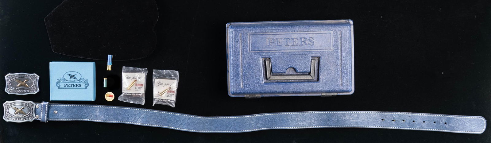 LOT OF ASSORTED PETERS CARTRIDGE COMPANY: MEMORABILIA. Lot consists of: 1) Blue synthetic Peters ammunition box. 2) Peters belt buckle adorn with a brass mallard above a banner that reads "FINE AMMUNITION SINCE 1887" and "PETERS". Rear is mar