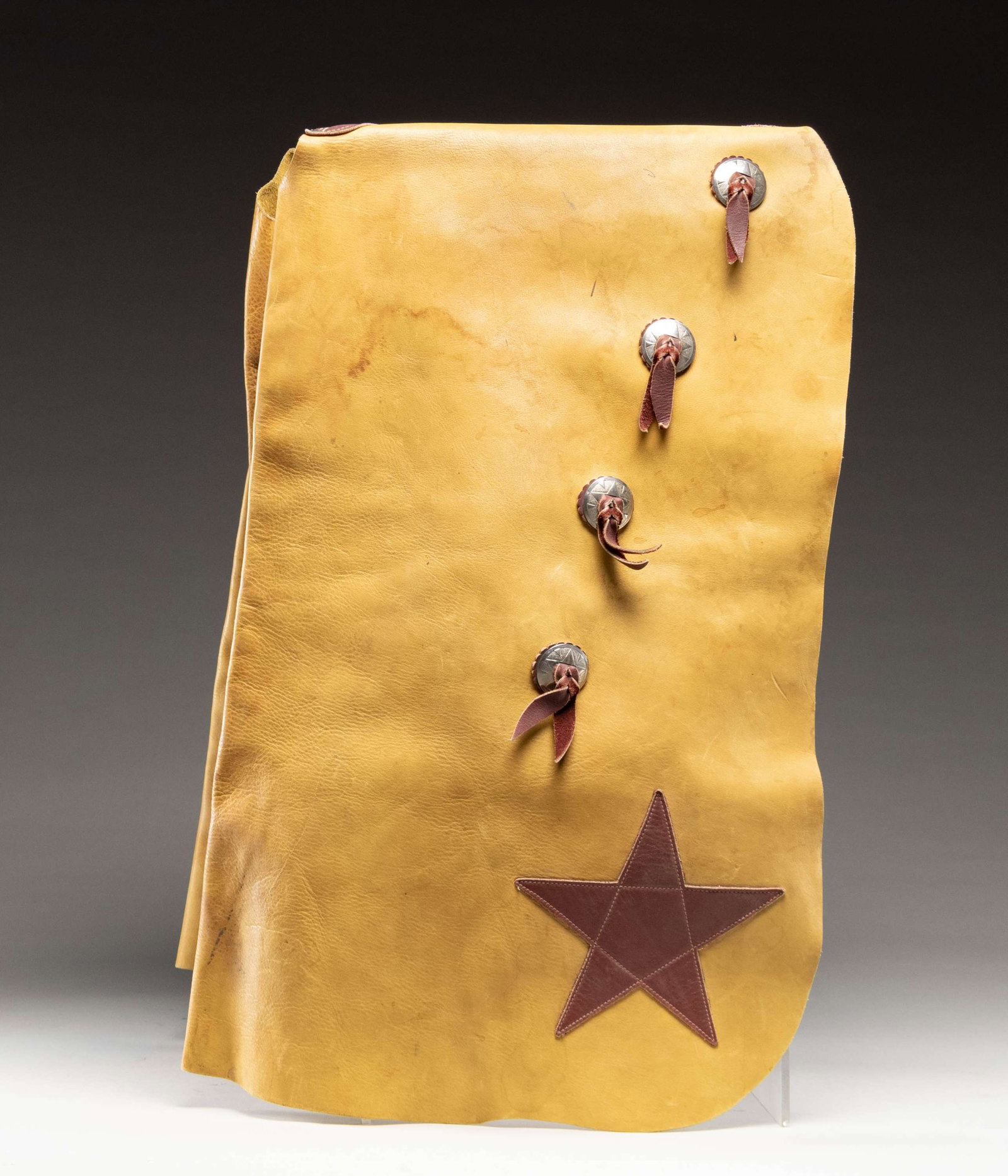 VICTOR ARIO SADDLERY OF GREAT FALLS, MONTANA: LEATHER CHAPS. Tan & brown leather chaps measures approx. 34" x 18" w/ plated conchos. CONDITION: very good overall showing light handling marks & stains. (02-25256/MD). NON-GUN. $300-500.