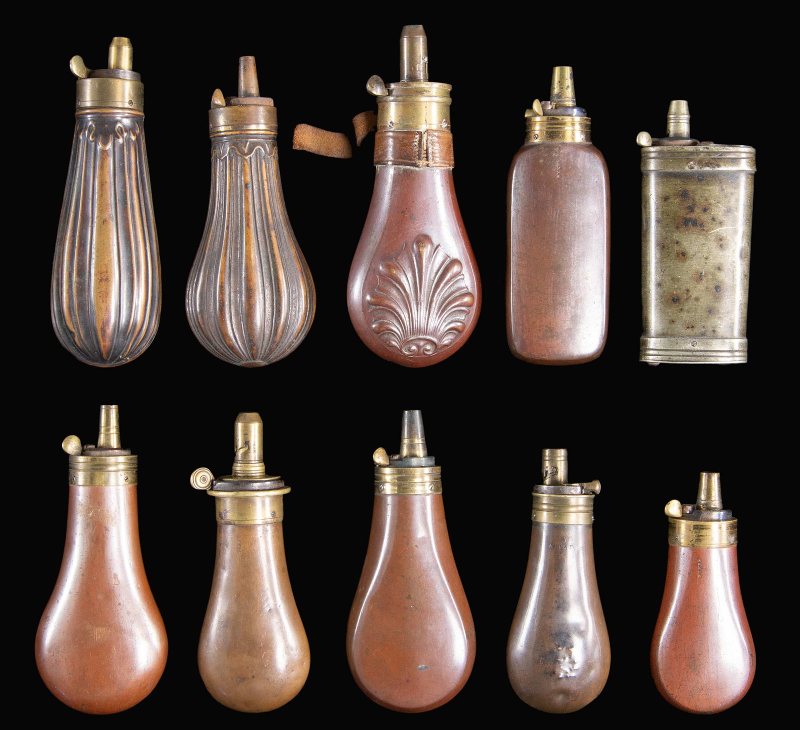 TEN DIFFERENT PISTOL FLASKS.: 10 flasks ranging from 3" to 5" including: 3" Sykes with most varnish retained, 4.5" Skyes, 5" clamshell decorated Patent marked with leather collar & much varnish, white metal 4" Dixson hallmarked