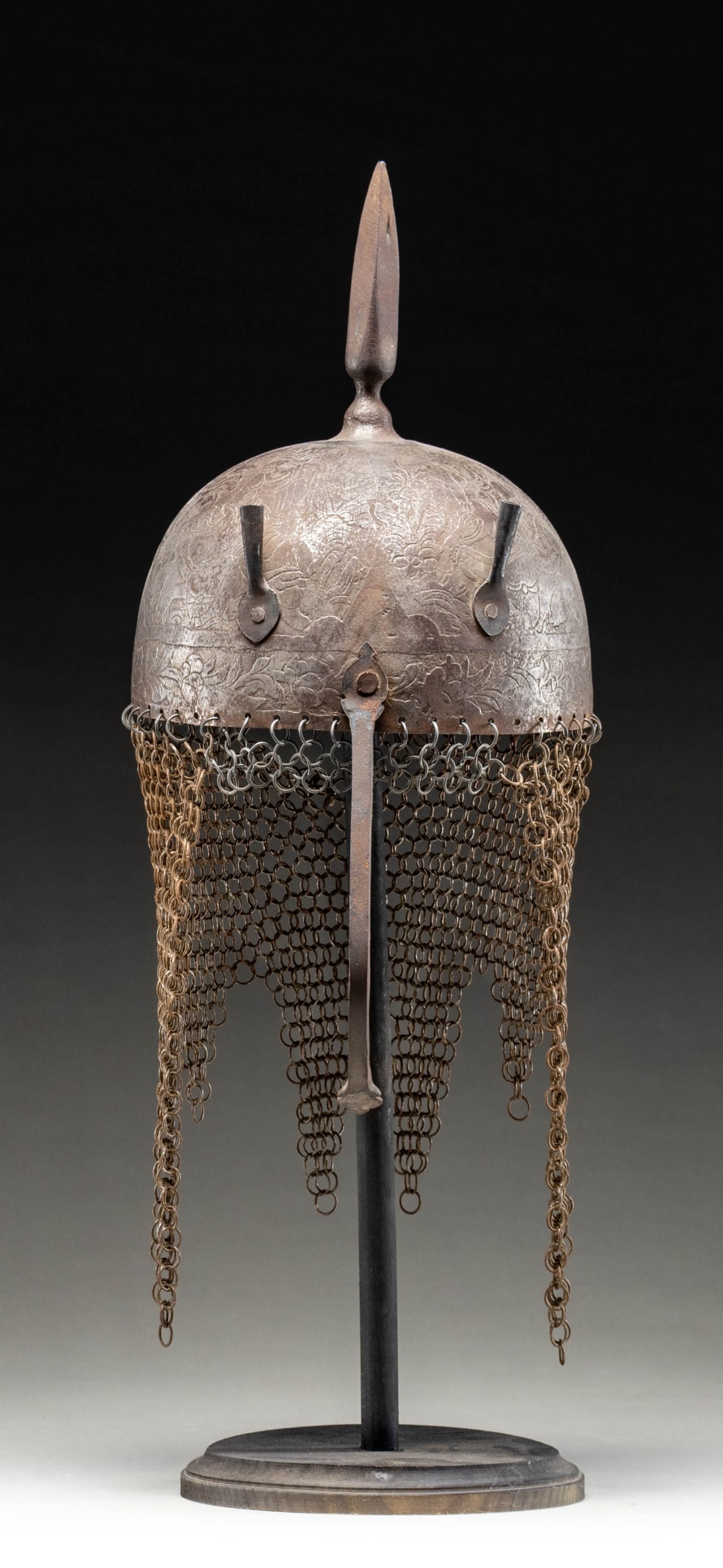 18TH OR 19TH CENTURY PERSIAN KULAH KHUD HELMET.: This fine Persian steel helmet measures approximately 19" from the base of the aventail to the top of the spike. The spike has 4 facets and the skull is decorated with foliate motifs and mounted soldi