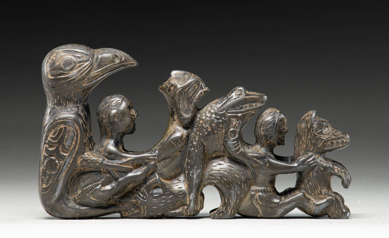 NATIVE AMERICAN NORTHWEST CARVED STONE TOTEM.: A large visually impactful steatite/soapstone carving likely of Northwest Native American origin. This totem depicts, in descending order, an eagle, a seated man, a backwards seated elderly woman, a