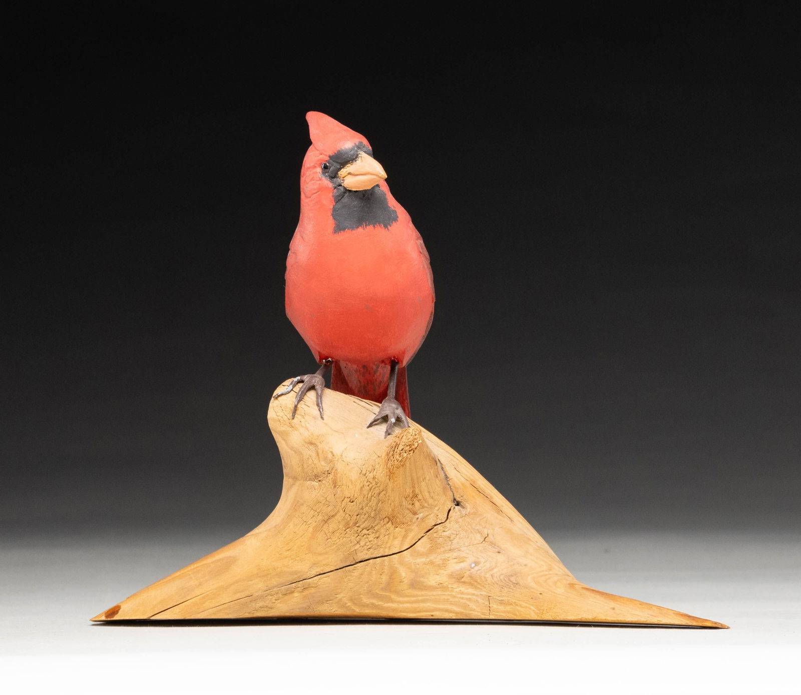 ROBERT & VIRGINIA WARFIELD CARDINAL CARVING.: Cardinal carving produced by Robert and Virginia Warfield of Jaffrey, NH. Carving consists of a painted cardinal standing atop a driftwood base. Underside of base exhibits a handwritten "Cardinal",