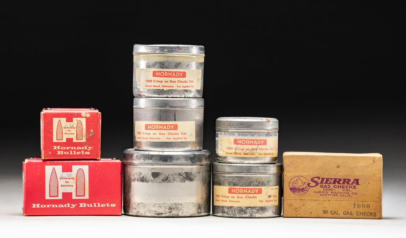 9 CONTAINERS OF HORNADY & SIERRA GAS CHECKS.: 1 - Box Hornady 25 cal. gas checks; appears unopened.1 - Tin Hornady 6.5mm that is about 1/4 full; written on label "BAD".1 - Box Hornady 30 cal. appears full.1 - Box Sierra 30 cal. appears full.1 -