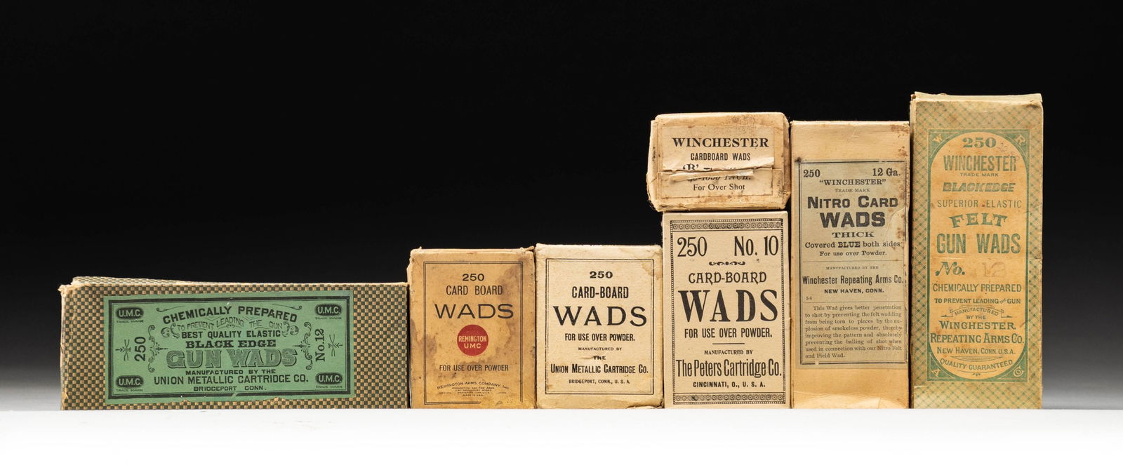 7 VINTAGE BOXES OF GUN WADS.: Lot includes: 3 Winchester, 1 Peters, 2 UMC, 1 Remington UMC. CONDITION: boxes in good to fair overall condition showing stains, tears & marks. Most appear more the 3/4 full. PROVENANCE: Norman