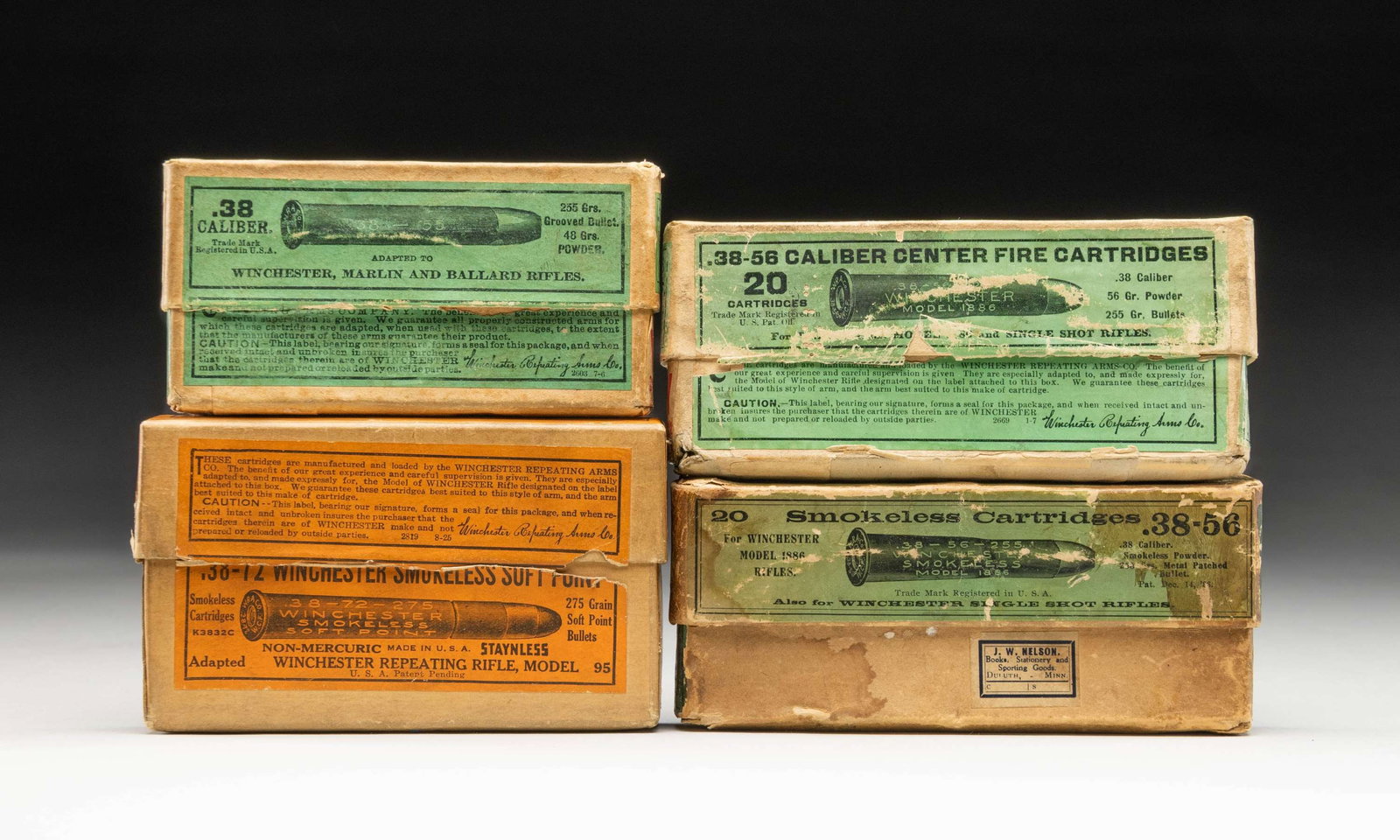 4 ANTIQUE BOXES OF WINCHESTER AMMO.: Very good 20 round 2 piece boxes with minimal scuffs; partials and mixed lots noted. 1). 38-56 Win. green labeled box with small retailer label from J. W. Nelson of Duluth, Minn. Water stains on box h