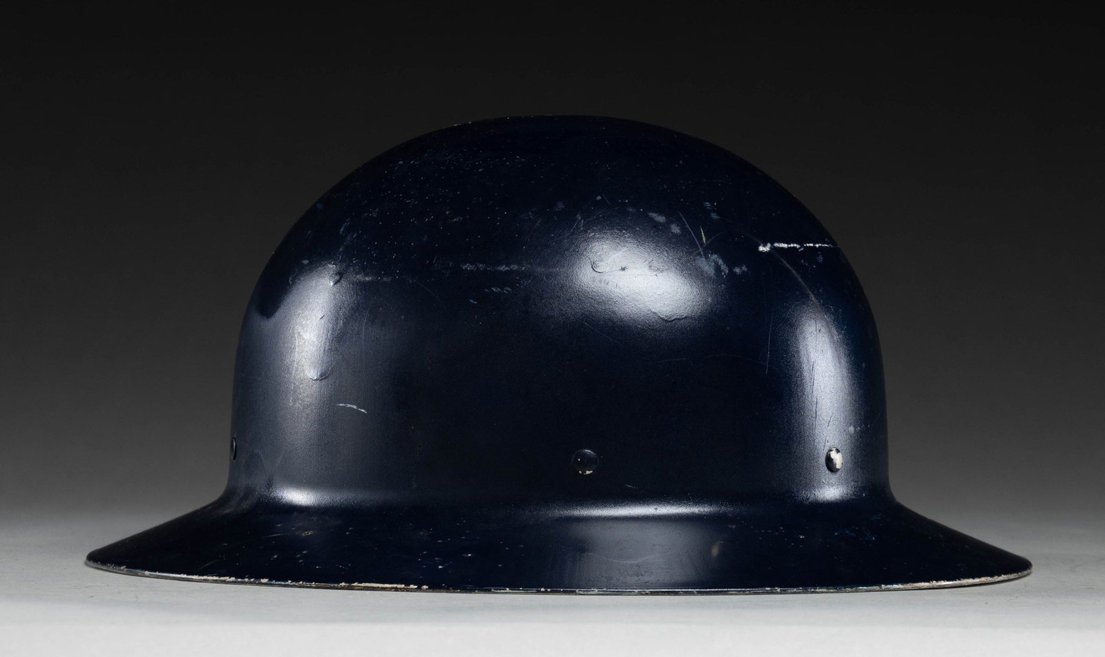 UNMARKED BRODIE HELMET.: Unmarked Brodie style helmet with an old dark blue exterior repaint possibly police or Civil Defense. Interior has gray paint. Liner & chinstrap present. CONDITION: liner is coming loose tears along