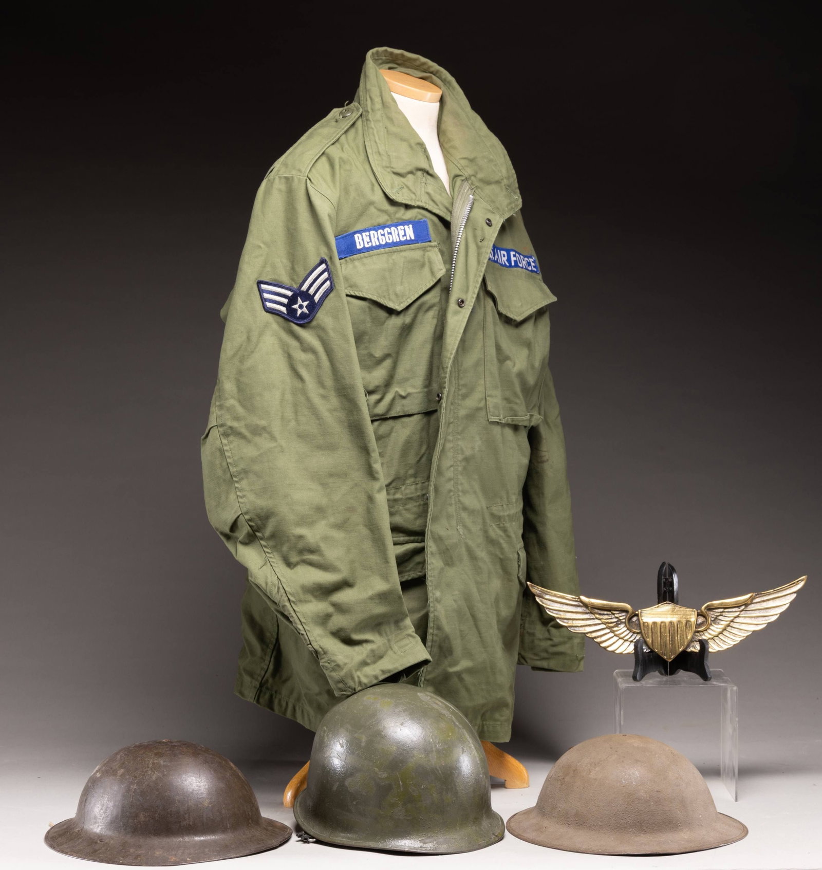 GROUP OF US MILITARIA INCLUDING THREE HELMETS AND: VIETNAM ERA AIR FORCE FIELD JACKET. Lot consists of: 1.) Two U.S. Model 1917 steel helmets. Helmets are painted green without insignias. Markings are not legible due to paint. Both having leather