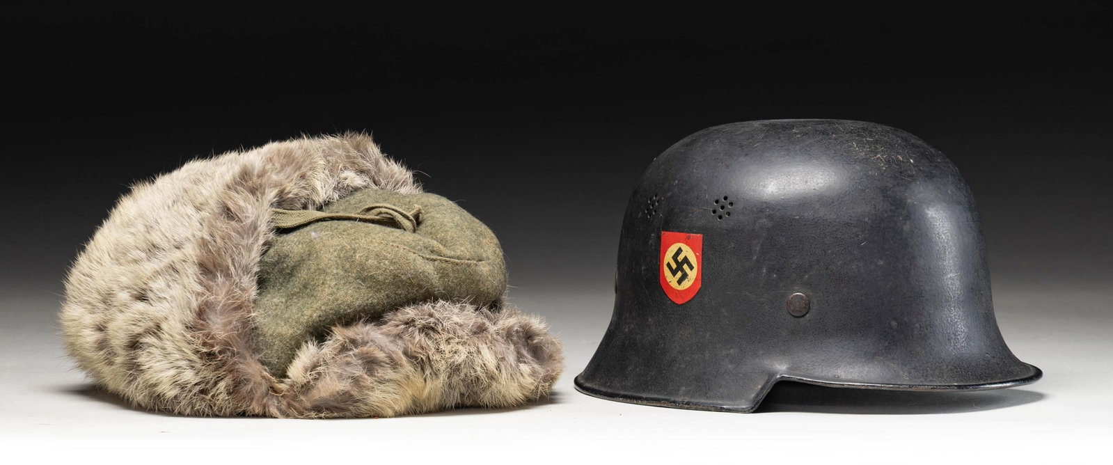 WWII GERMAN POLICE HELMET AND ARMY WINTER FUR CAP.: 1) A very nice example of a WWII German civic police helmet with a black painted finish showing a national decal on the right and a black police decal on the left. A partial stamp on the inside right