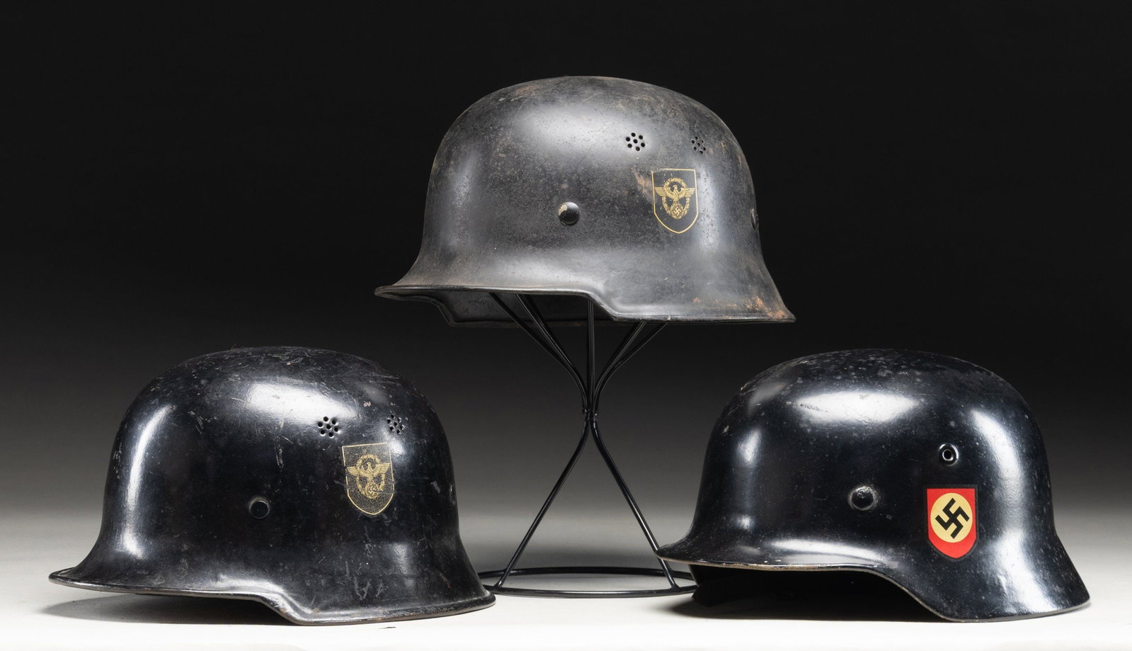 3 WWII GERMAN HELMETS.: 1) A good example of a WWII German Police civic model curved dip helmet with a black painted finish showing a Police decal of the left side and a Party decal on the right. There are no stampings on