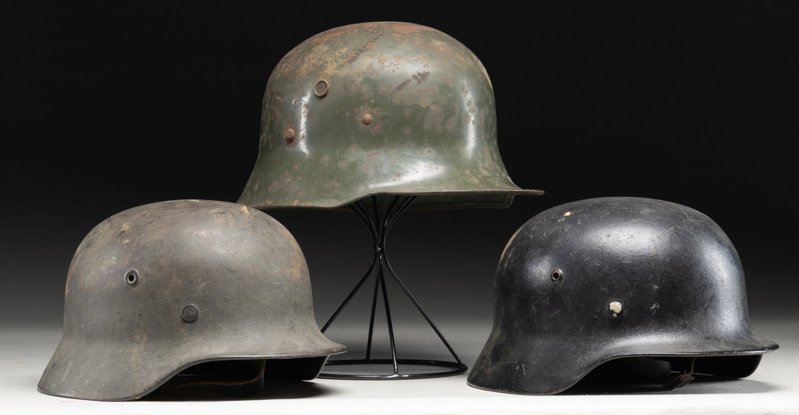 3 WWI & WWII GERMAN HELMETS.: 1) A very interesting WWII German M35 helmet painted black with a single Wehrmacht style eagle decal that definitely shows gold tones. The black paint does seem to be the original color of the helmet