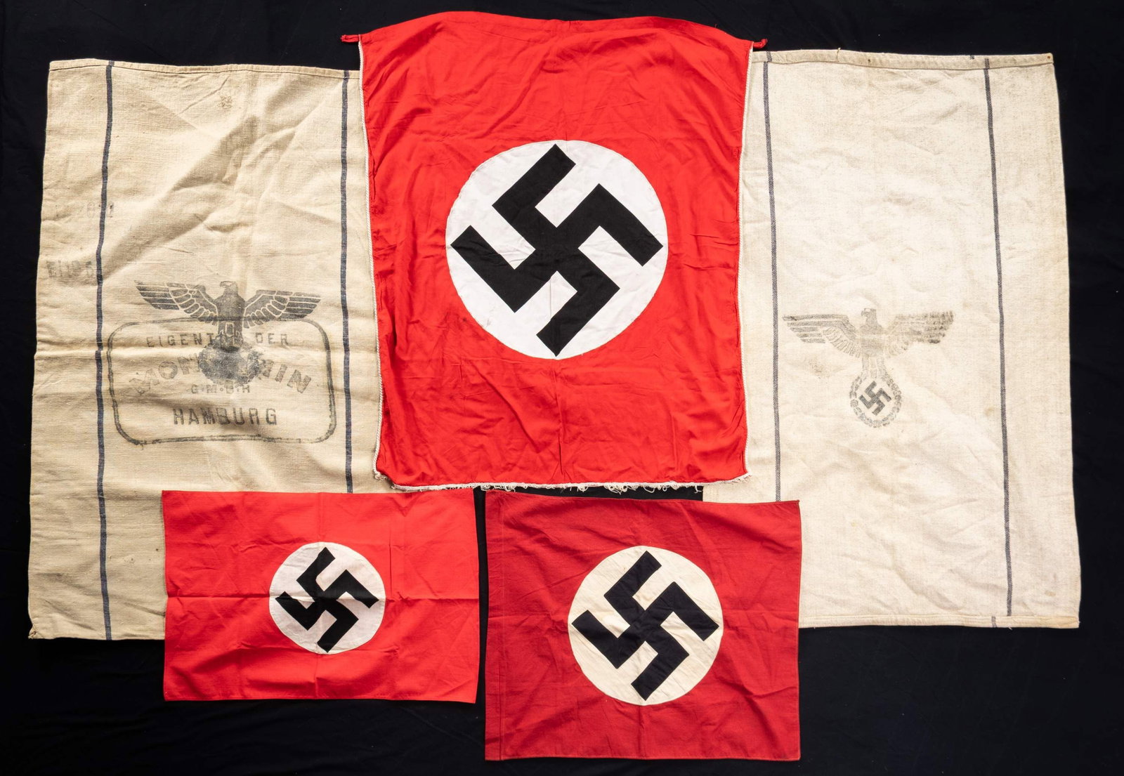 WWII GERMAN FLAGS, BANNER, AND PROVISION BAGS.: This lot includes 2 Large heavy burlap grain/provisions bags with Wehrmacht eagles on one side and "H.Vpfl." on the other. They are dated "1938" and "1943" respectively, 1 Party flag measuring 23" x 1