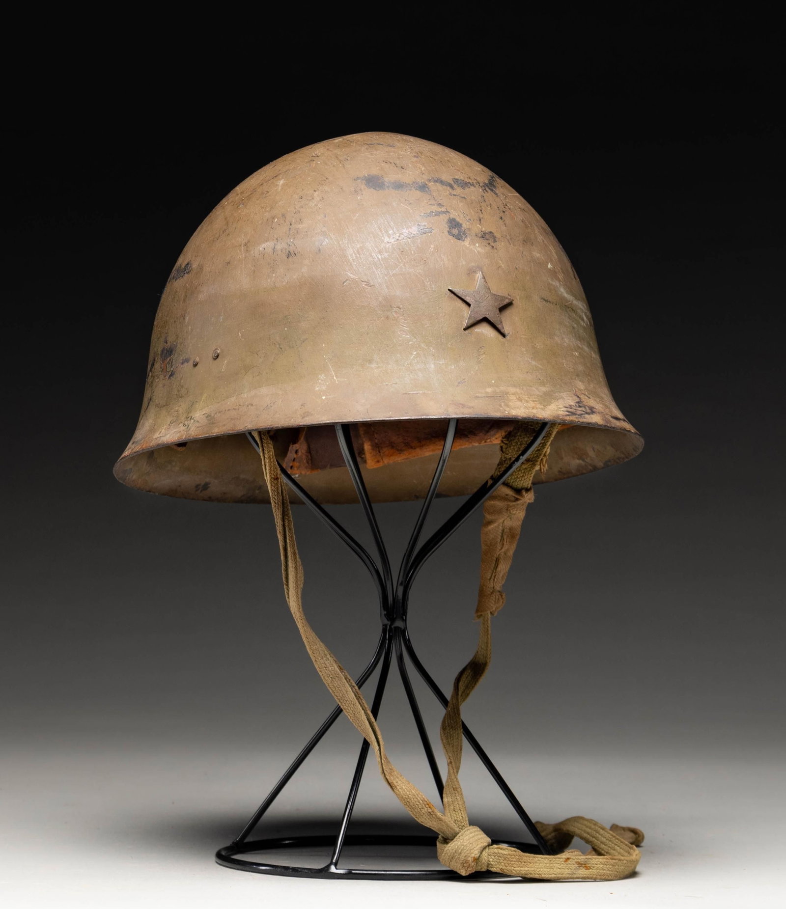 WWII JAPANESE ARMY HELMET.: A fine example of a WWII Japanese army helmet with a dull field green finish and a metal star on the front. The interior has a 3-pad leather liner and a cotton canvas chinstrap. There is a single