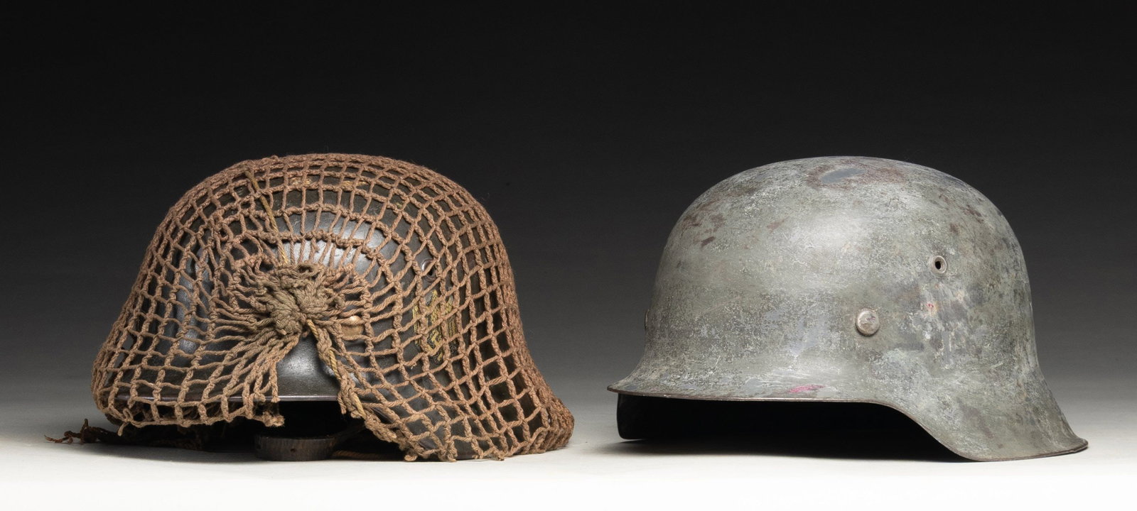 LOT OF 2 GERMAN WWII M40 & M42 STAHLHELMS.: Lot of 2 German World War II M40 & M42 stahlhelms, including: 1) German WWII single decal M40 stahlhelm. Helmet exhibits a gray painted exterior and a single Heer decal present on the left, featuring 