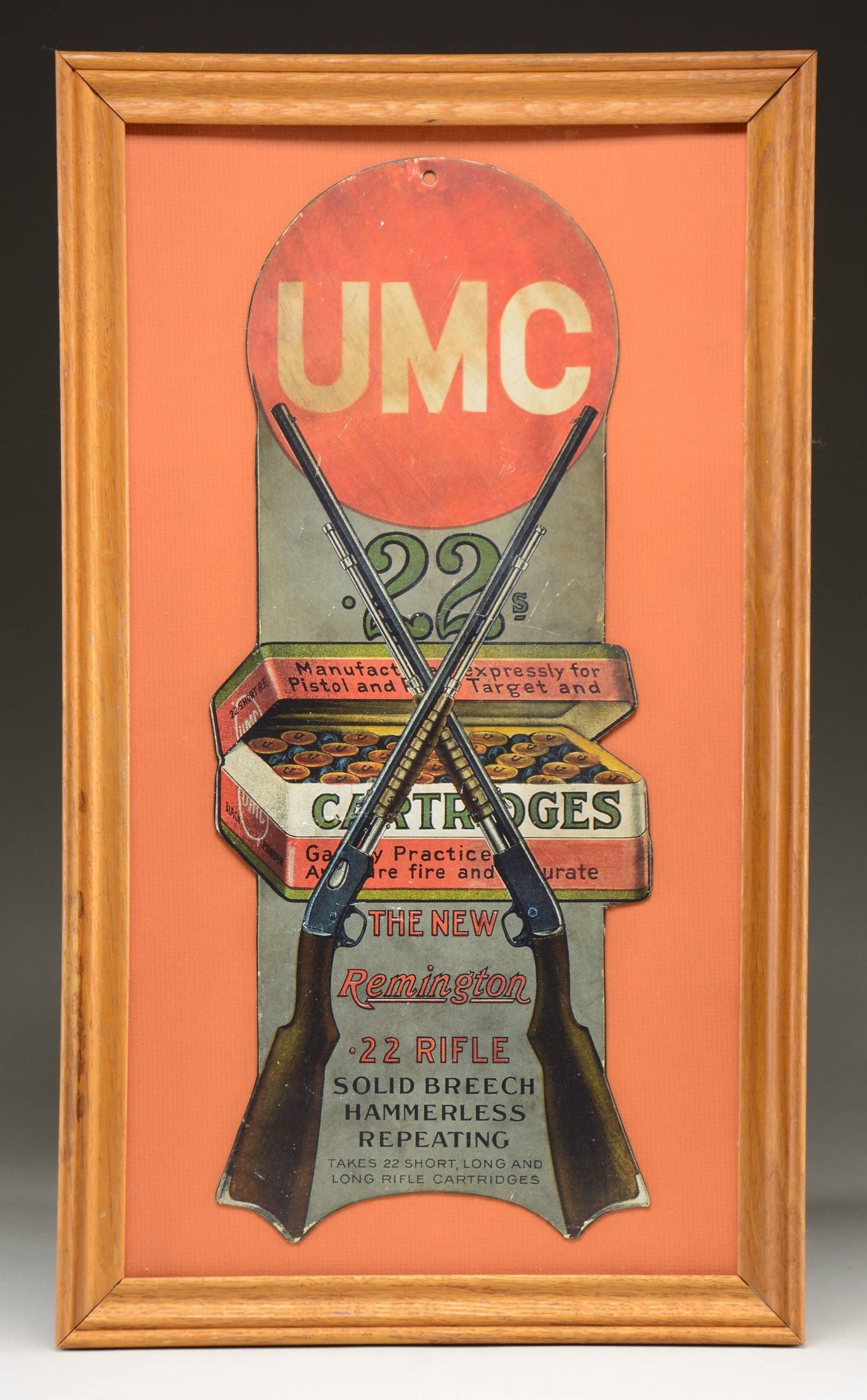 REPRODUCTION UMC CARTRIDGES & REMINGTON RIFLE: CARDBOARD CUTOUT ADVERTISEMENTS. Topped by the red circular UMC trademark. Pictures a red & green box of UMC 22 cal. cartridges behind a crossed pair of Remington Model 12 pump rifles against a gray b