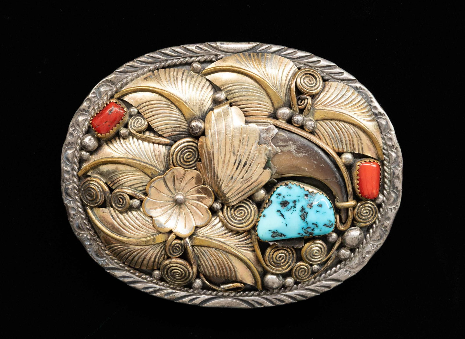 "JERRY BAHE" SIGNED NAVAJO SILVER TURQUOISE & BEAR: CLAW BELT BUCKLE. 3.5" x 3" oval buckle with gilded floral overlay, red coral, turquoise, and bear claw decoration, Bahe family of Navajo silversmiths is well known. 70 grams. CONDITION: belt loop has