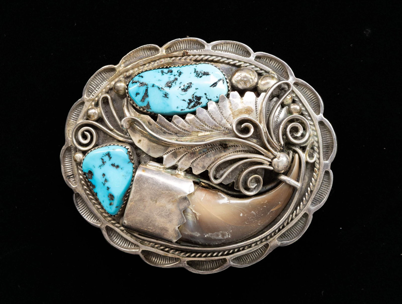 "GENEVA APACHITO" SIGNED SILVER NAVAJO TURQUOISE &: BEAR CLAW BELT BUCKLE. 3.25" x 2.5" oval bear claw & turquoise decorated, stamped signature "APACHITC / STERLING", Geneva Apachito, Soccoro, NM, born 1969, 80 grams. CONDITION: good. (02-27023-1/JS). 