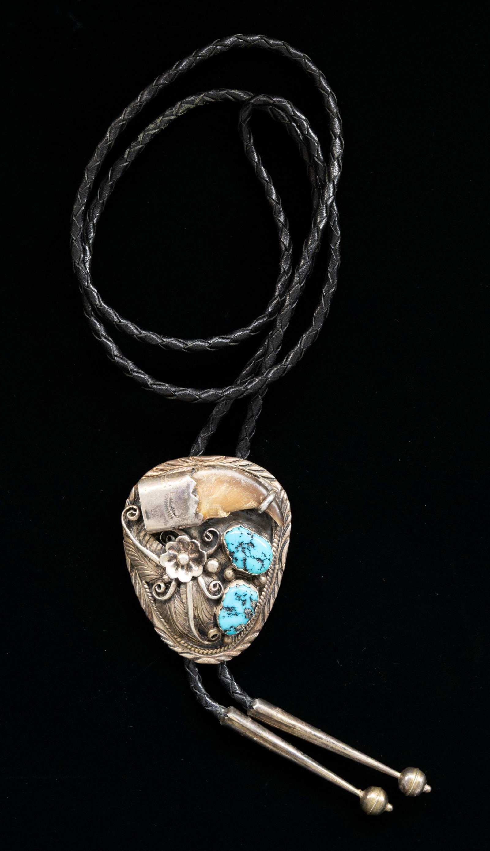 VINTAGE SILVER NAVAJO TURQUOISE & BEAR CLAW BOLO.: 2.25" x 2" turquoise and bear claw decoration, woven leather bolo with silver tips, sun signed, total weight 52 grams. CONDITION: good. (02-27025-2/JS). NON-GUN. $200-400.