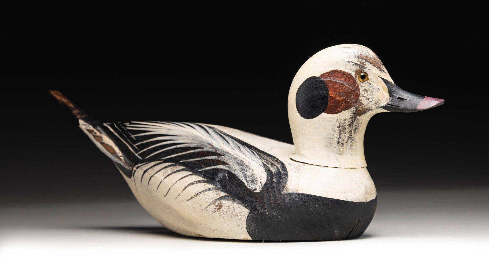 G.F. CRANWELL, "OLD SQUAW DRAKE" DECOY.: "Old Squaw Drake" decoy crafted by G.F. Cranwell. Decoy measures approx. 17" in length, featuring black, white, and brown plumage, with a black and gray beak, as well as yellow glass eyes. Underside i