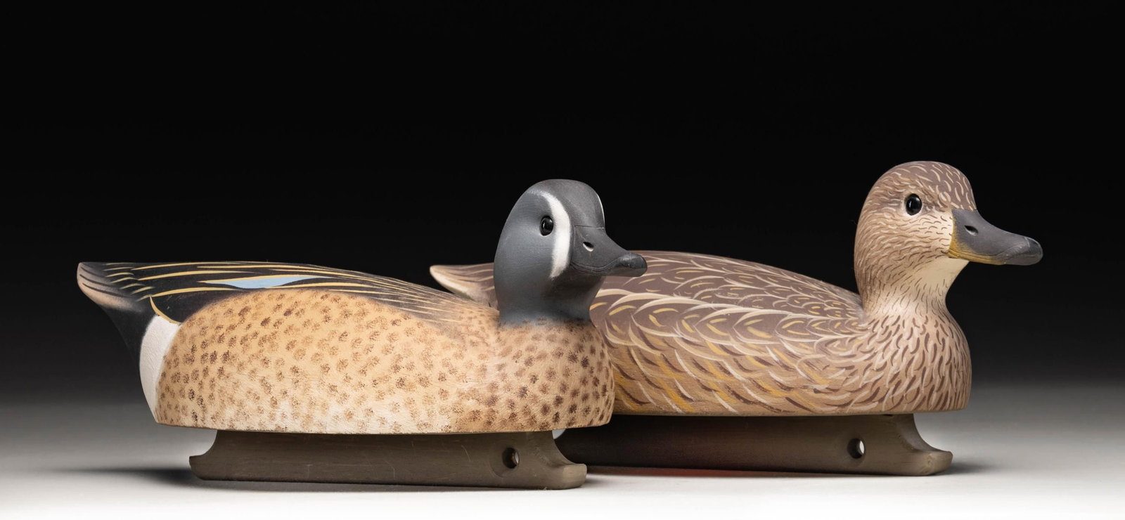 ROBERT CAPRIOLA, "1995" PAIR OF BLUE-WINGED TEAL: DRAKE & HEN DECOYS. 1) Blue-winged teal drake crafted by Robert Capriola in 1995. Decoy measures approx. 14" in length, featuring brown, black, white, and blue plumage, with a black bill and glass eye