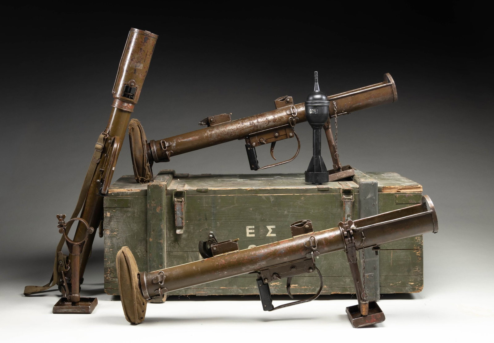 CRATE OF 3 PIAT LAUNCHERS.: Three crated WW2 era British PIAT (Projector, Infantry, Anti-Tank) launchers in what appears to be a Greek crate. Three springs are also present one for each launcher. The PIAT is known for its unique