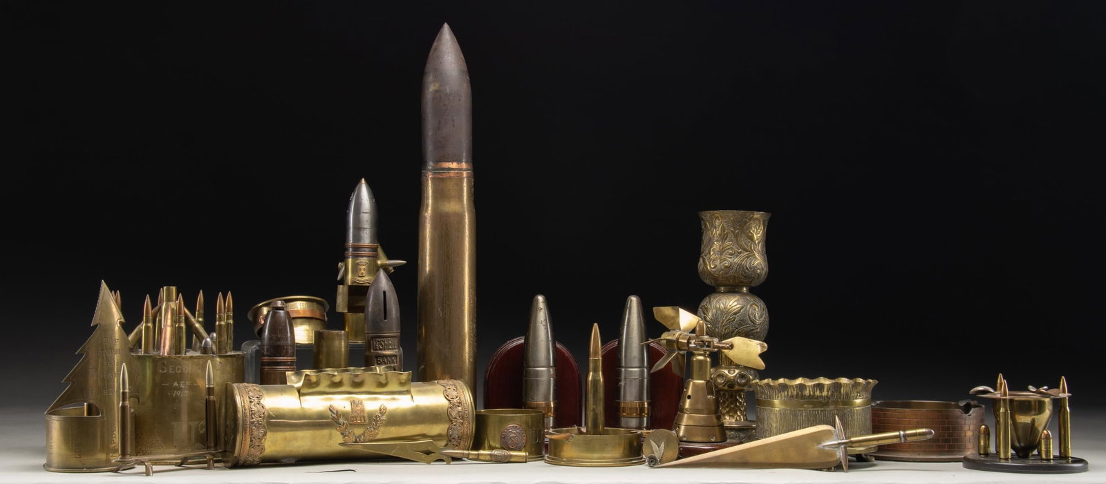 LARGE GROUPING OF WWI & WWII TRENCH ART.: This interesting grouping features a grouping of trench art from both WWI & WWII spent artillery munitions. It contains ash trays, vases, candle holders, desk trinkets, and other nicely executed