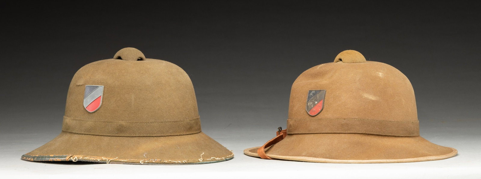 LOT OF 2 GERMAN WWII DAK SUN HELMETS.: Lot of 2 German WWII DAK (Deutsches Afrika Korps) sun helmets. Pith construction with leather visor trim and 2 shielded medallions. x1 helmet ink stamped on the interior with an illegible marking