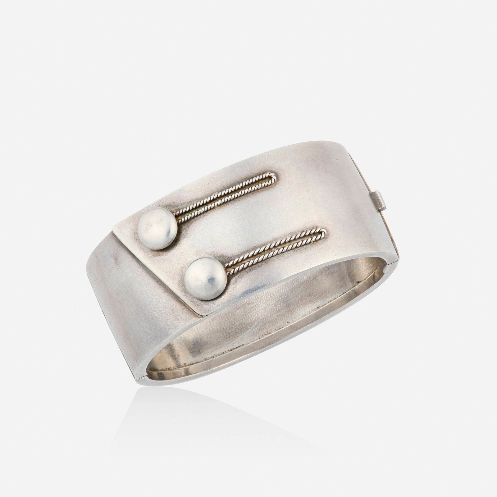 Victorian, Sterling silver bracelet: Victorian Sterling silver bracelet The hinged bangle bracelet designed with faux buttons; 1879 Sterling silver Inner circ. 6.75 in, width 1.125 in; Gross weight 27.3 dwts This work will ship from Lamb
