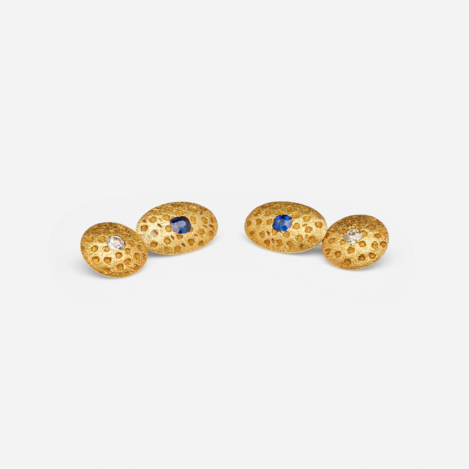 Victorian, Sapphire, diamond, and gold cufflinks: Victorian Sapphire, diamond, and gold cufflinks Each of hammered design, set with an oval-cut sapphire and old mine-cut diamond; 1897 18k yellow gold 1.25 x 0.75 in; Gross weight 7.7 dwts This work