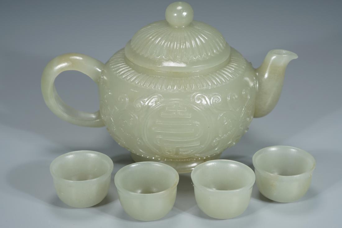 A WHITE JADE CARVING TEA SET: A white jade carving tea set. Dimensions: Five pieces Teapot: H 8.8 cm, W 13.7 cm, Weight 248.7 g. Each cup: H 2 cm, W 3.1 cm, Weight 13.6 g All measurements are approximate.