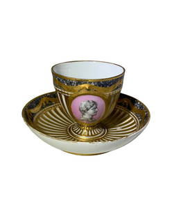 BEAUTIFUL ANTIQUE KPM PORCELAIN ROMAN CUP AND SAUCER: A KPM cabinet cup and saucer, each with a white ground and gilt highlights; the cup decorated with a medallion of an Augustus Caesar bust in profile. Scepter mark in blue under glaze, and black eagle