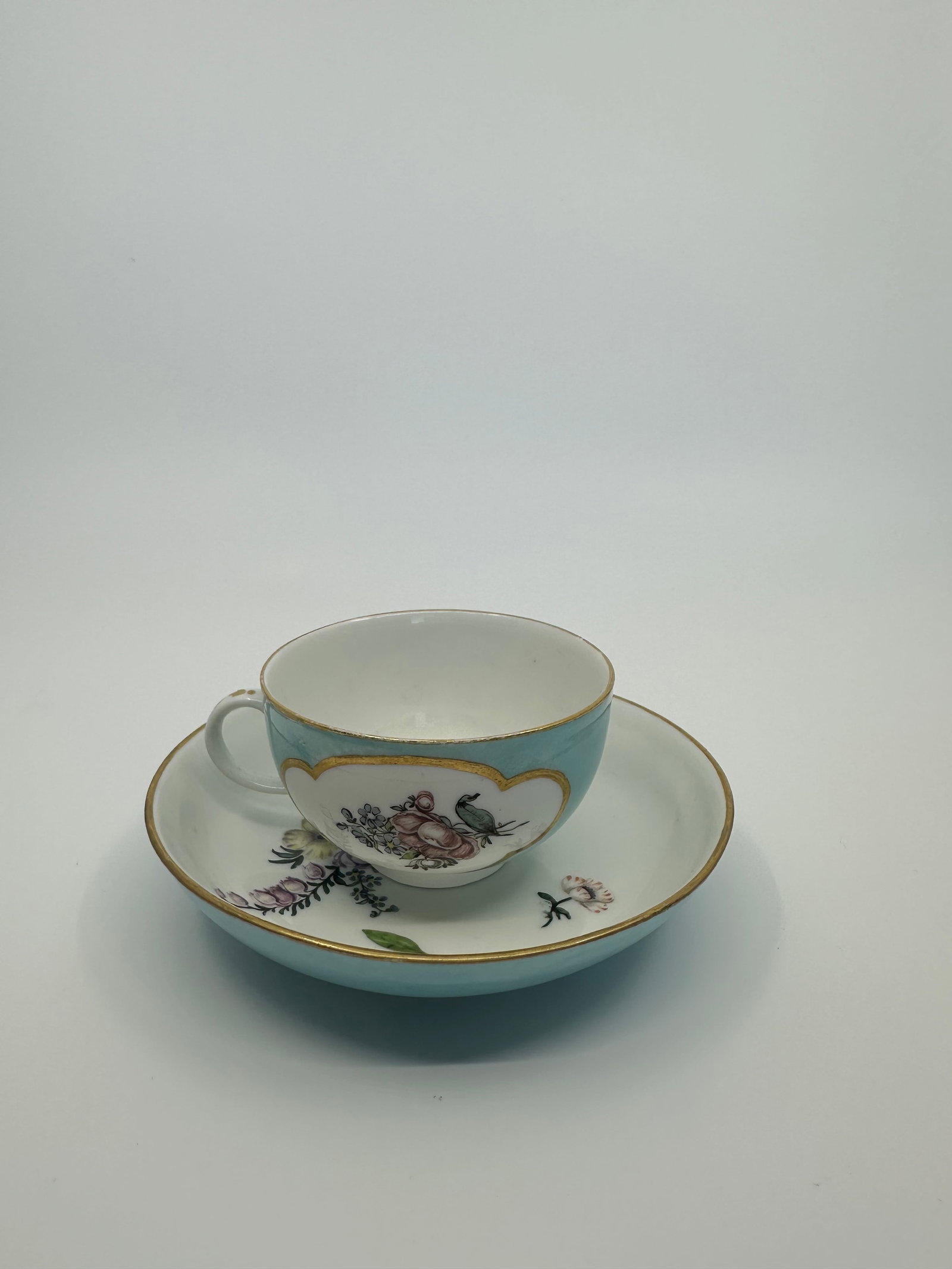 A MEISSEN PORCELAIN TURQUOISE-GROUND CUP AND SAUCER: A MEISSEN PORCELAIN TURQUOISE-GROUND CUP AND SAUCERCIRCA 1740, BLUE CROSSED SWORDS MARKS AND PRESSNUMMER Painted with deutsche Blumen, the teabowl with quatrefoil panels The saucer 4 in. (12 cm.) diam