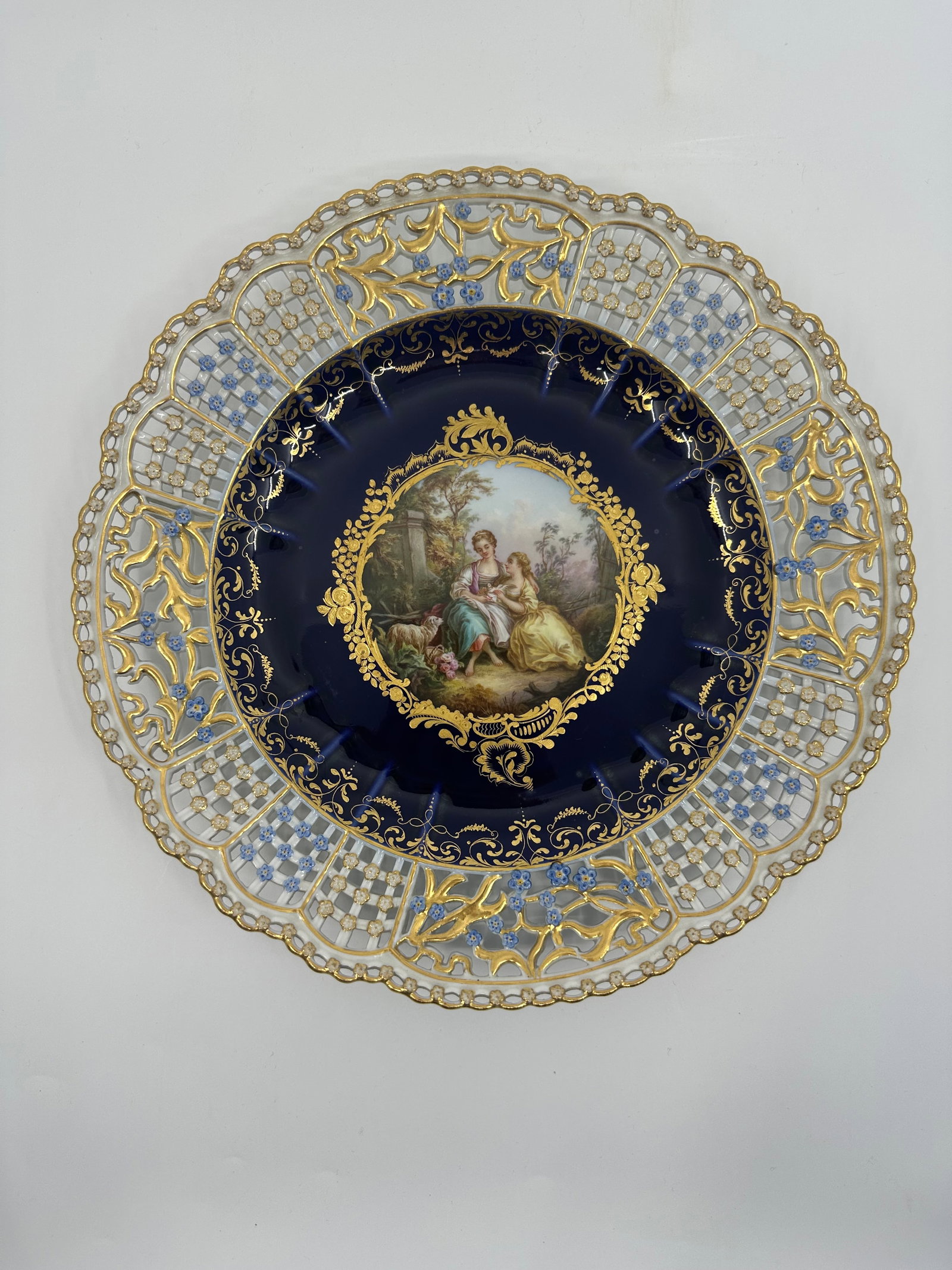 ANTIQUE MEISSEN PORCELAIN COBALT-BLUE GROUND RETICULATED CABINET PLATE: ANTIQUE MEISSEN PORCELAIN COBALT-BLUE GROUND RETICULATED CABINET PLATE. LATE 19TH CENTURY, BLUE CROSSED SWORDS MARKS, VARIOUS IMPRESSED NUMERALS. Finely painted Watteau scene 10 3/8 in. (26.3 cm.) dia