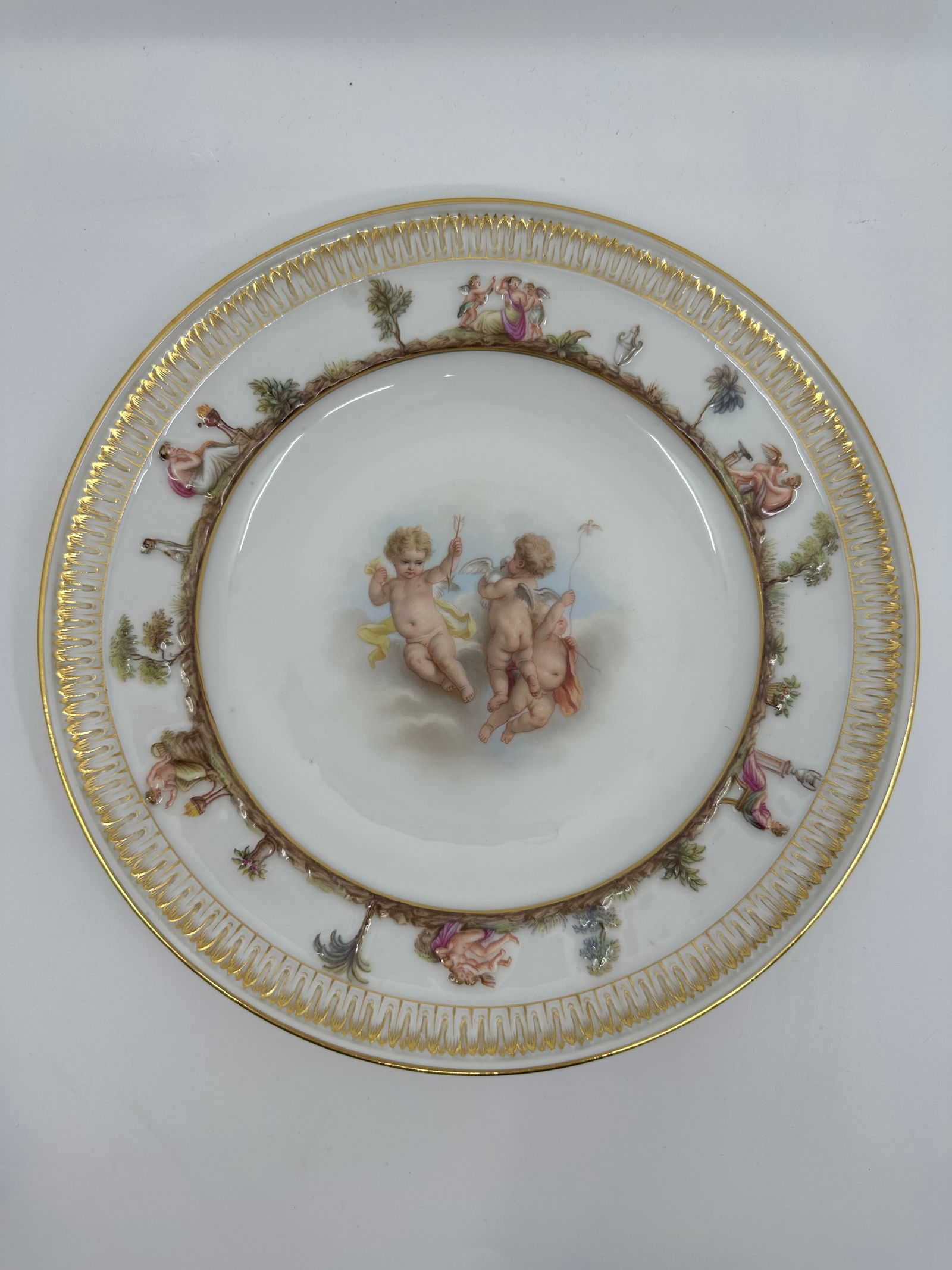 ANTIQUE MEISSEN PORCELAIN CAPODIMONTE PLATE: ANTIQUE MEISSEN PORCELAIN CAPODIMONTE PLATE LATE 19TH, BLUE CROSSED SWORDS MARK, IMPRESSED 44 Finely painted a putto scenes, the border molded with Capodimonte style mythological views and a band of s
