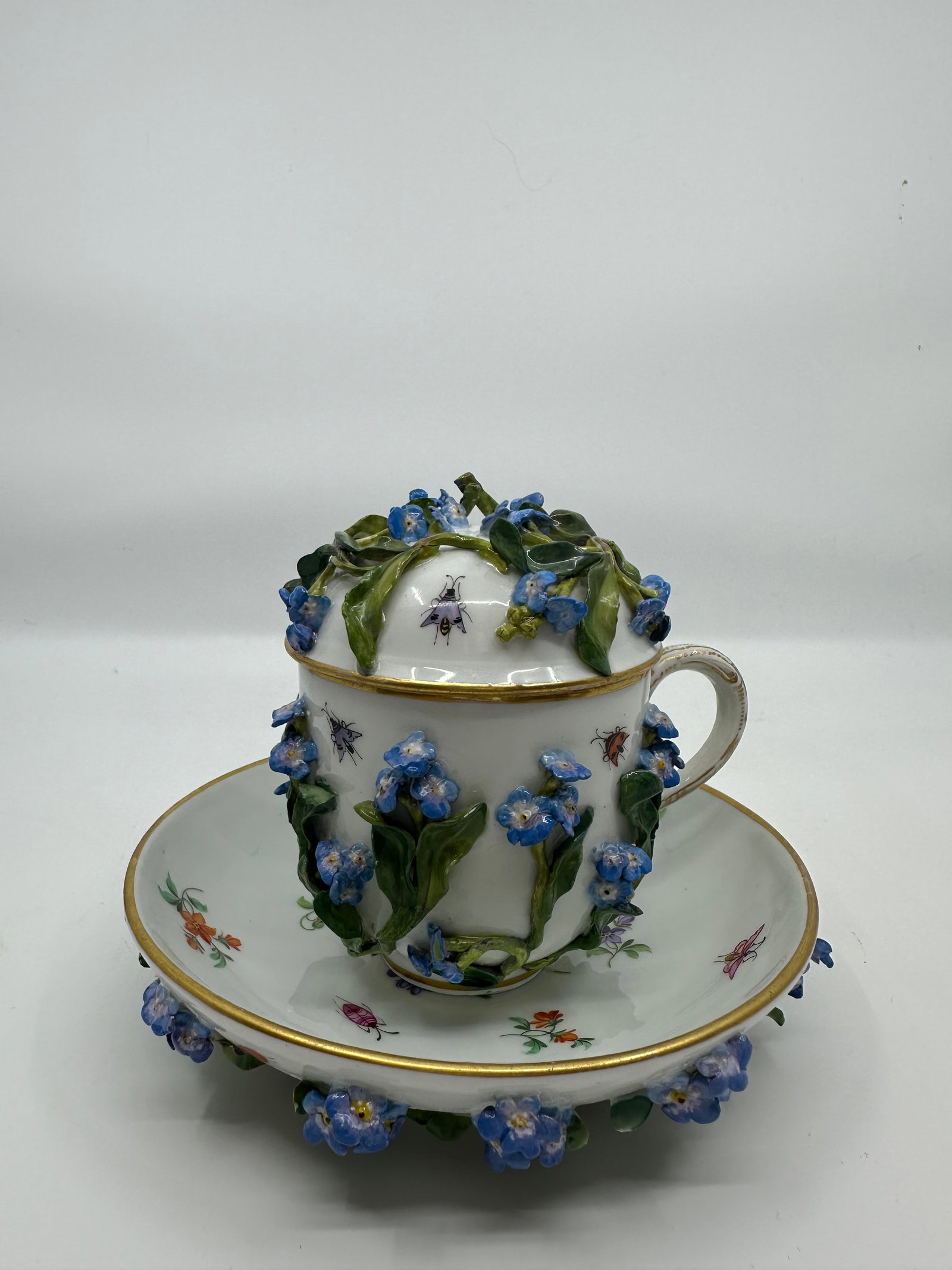 MEISSEN "FORGET ME NOT" CUP & SAUCER: Covered cup 4 1/4" and saucer 5 1/2", both having hand painted flowers, with leaves and bugs.